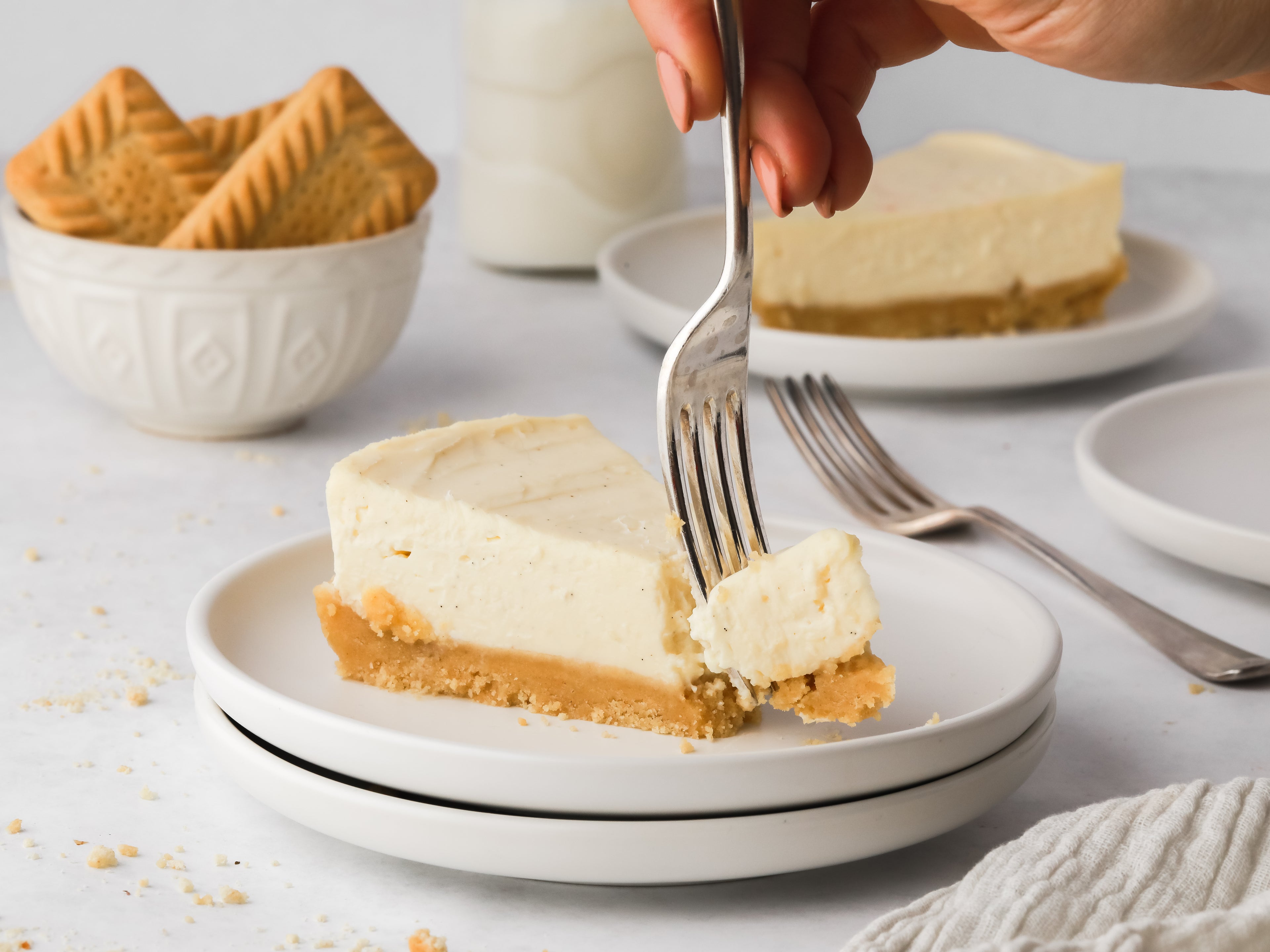Fork taking a bite out of a slice of vanilla cheesecake