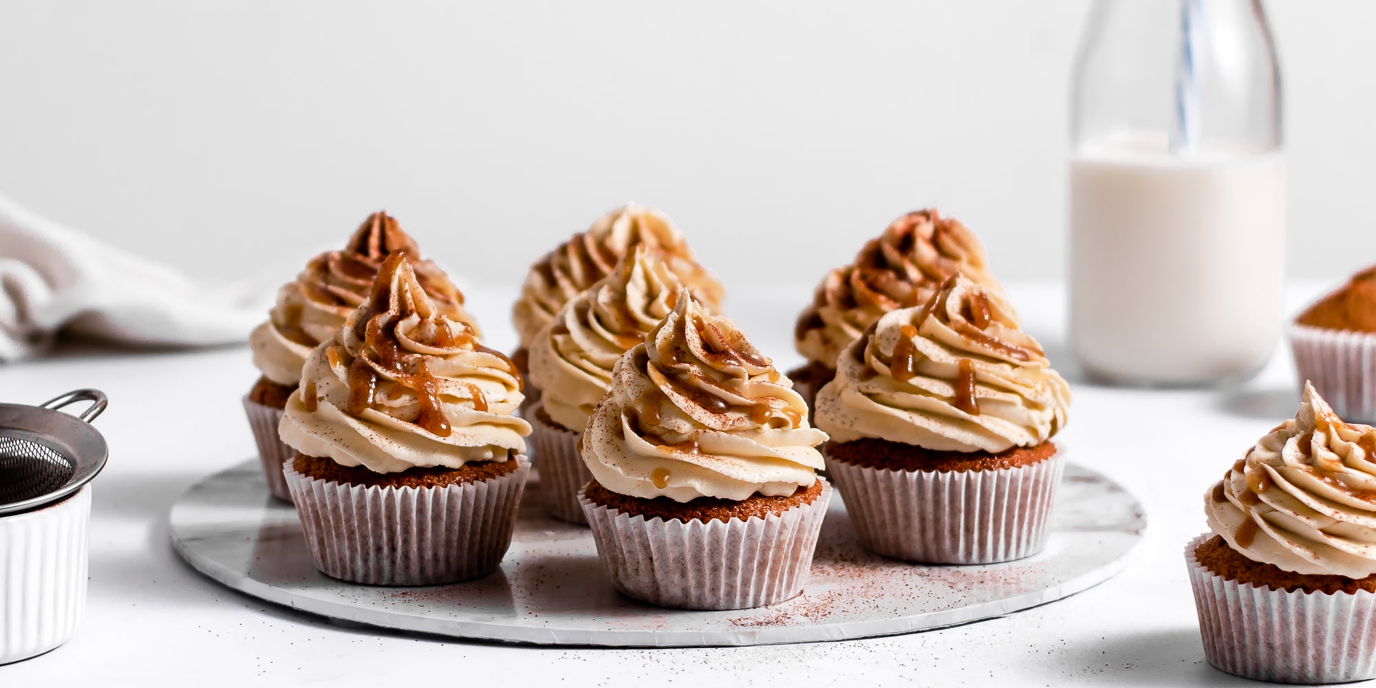 Close up of fresh batch of Gingerbread Cinnamon Cupcakes decorated with buttercream and drizzled with caramel