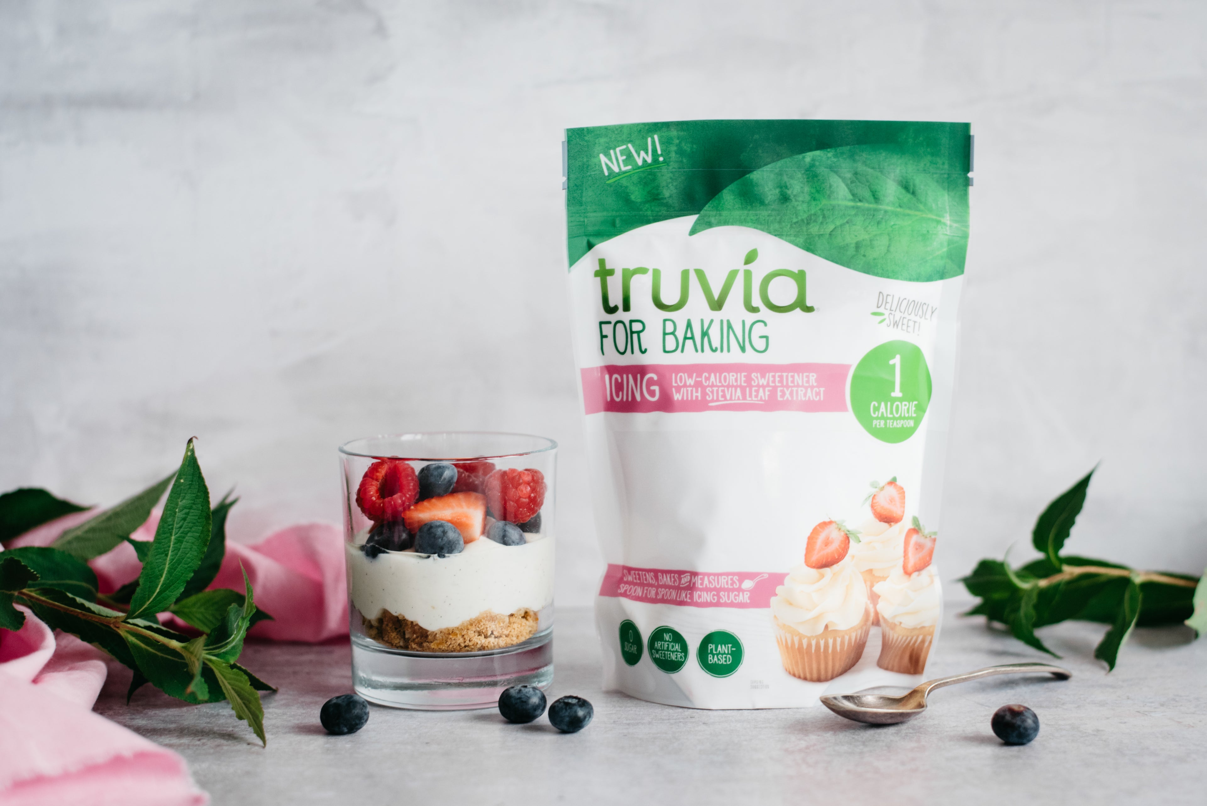 A no bake honey and berry cheesecake in a glass next to a packet of Truvia for baking - icing