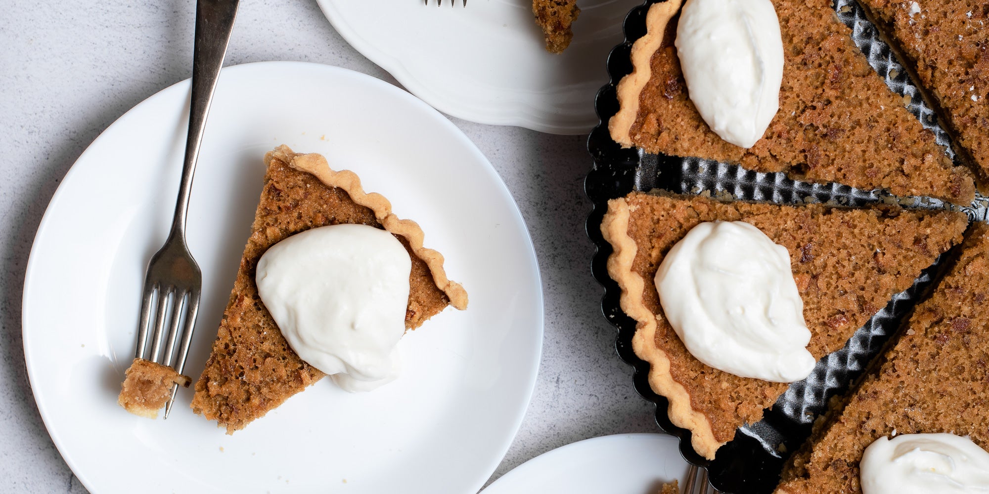 Treacle Tart cut into slices with dollop of cream, on a plate with a fork