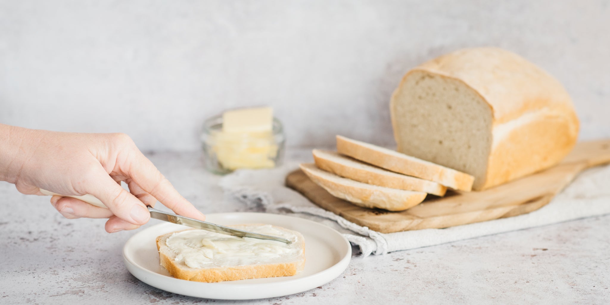 Spreading butter over slices of fresh homemade white bread