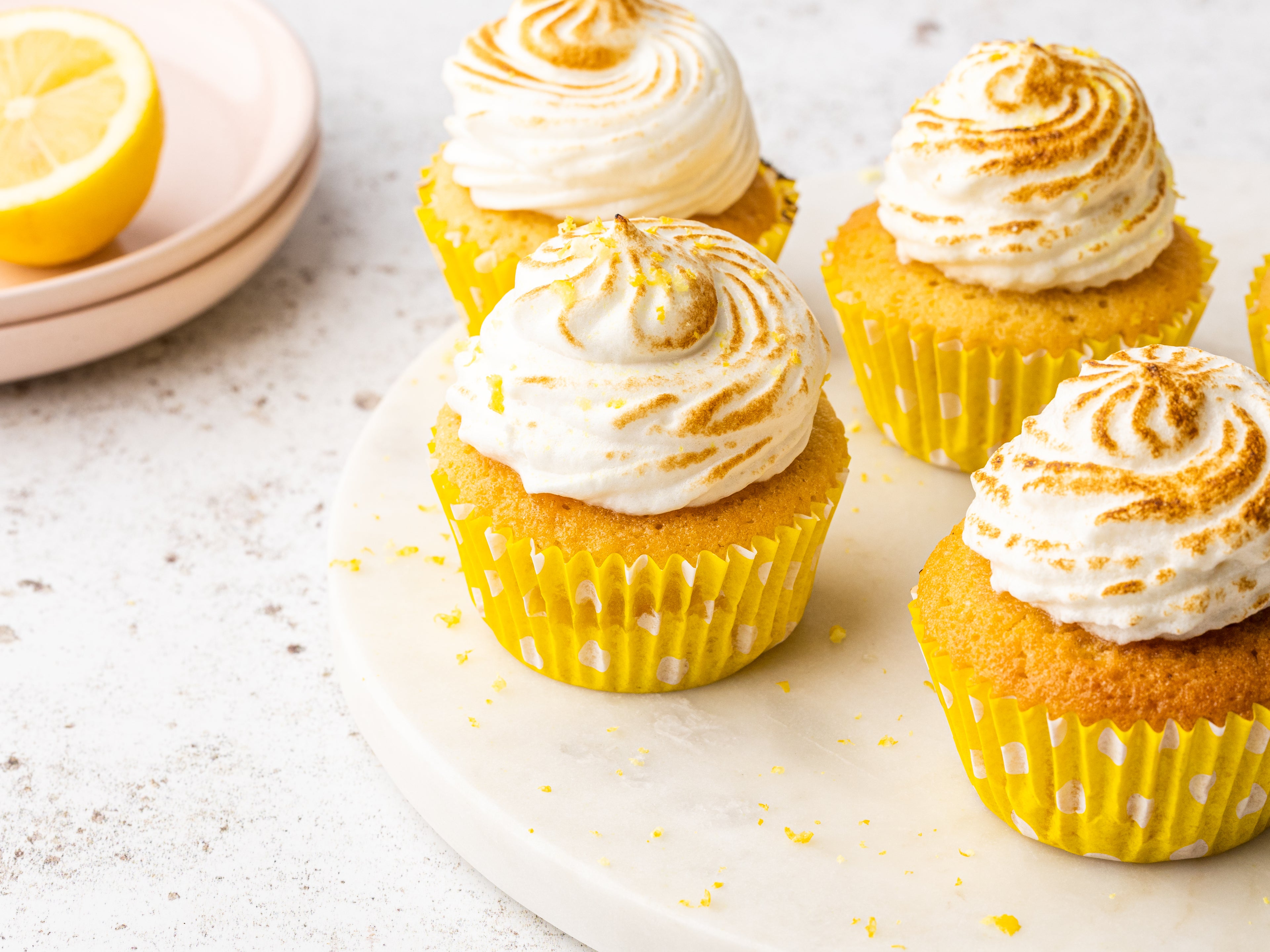 Close up shot of 4 lemon meringue cupcakes on a circular plate
