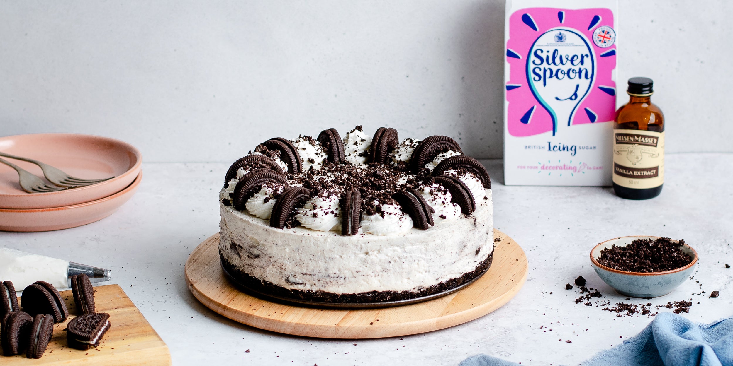 No-bake Oreo cheesecake on wooden plate with icing sugar, vanilla extract and Oreo cookies