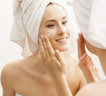 woman rubbing cream onto her cheek