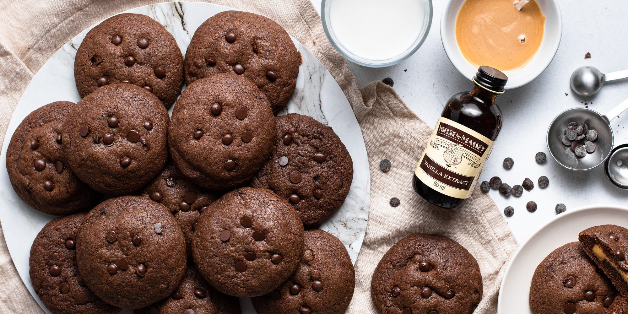 Chocolate & Peanut Butter Stuffed Cookies on a plate next to a bottle of Nielsen-Massey vanilla extract
