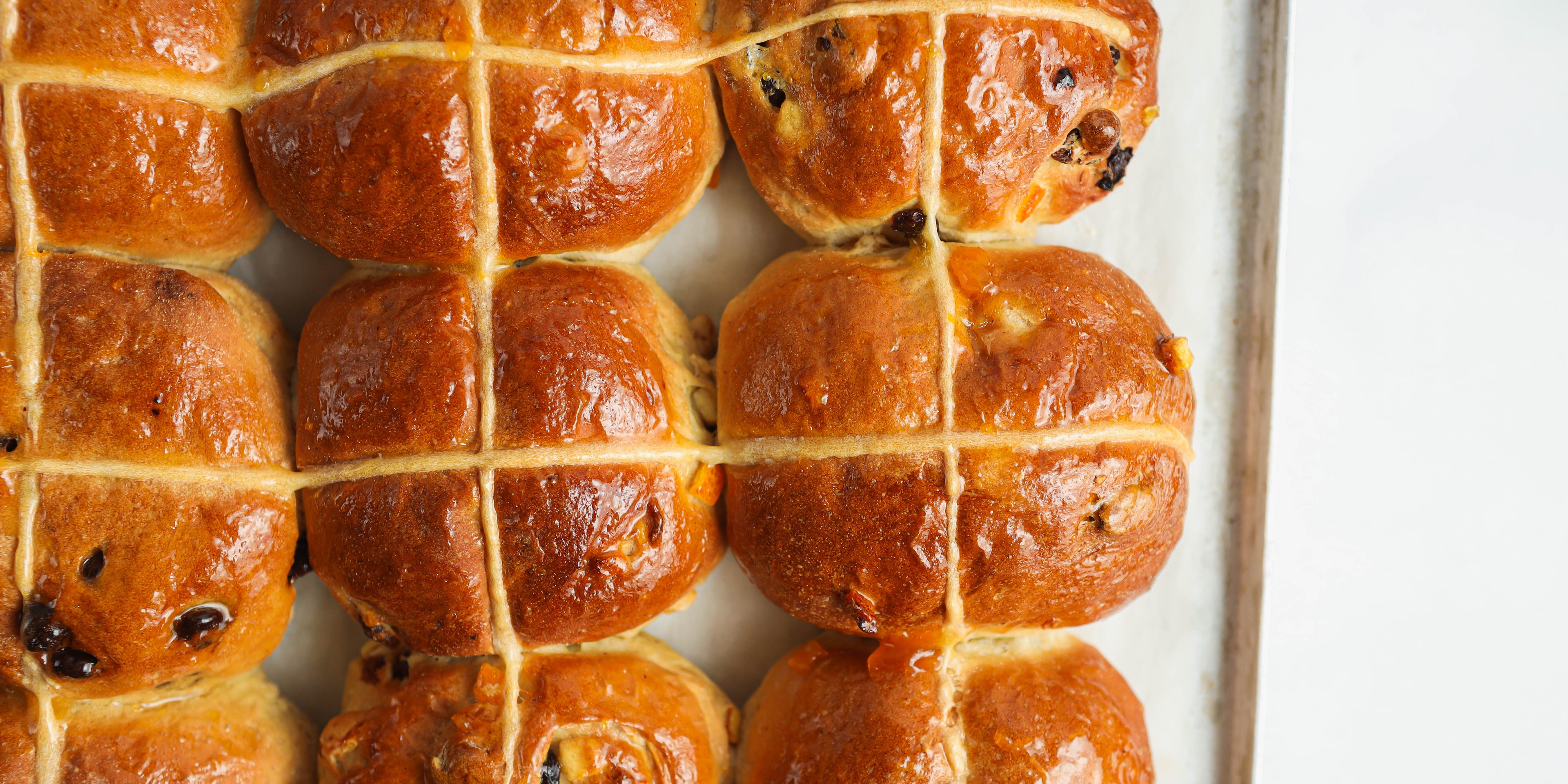 Close up of a freshly baked batch of Vegan Hot Cross Buns on a baking tray