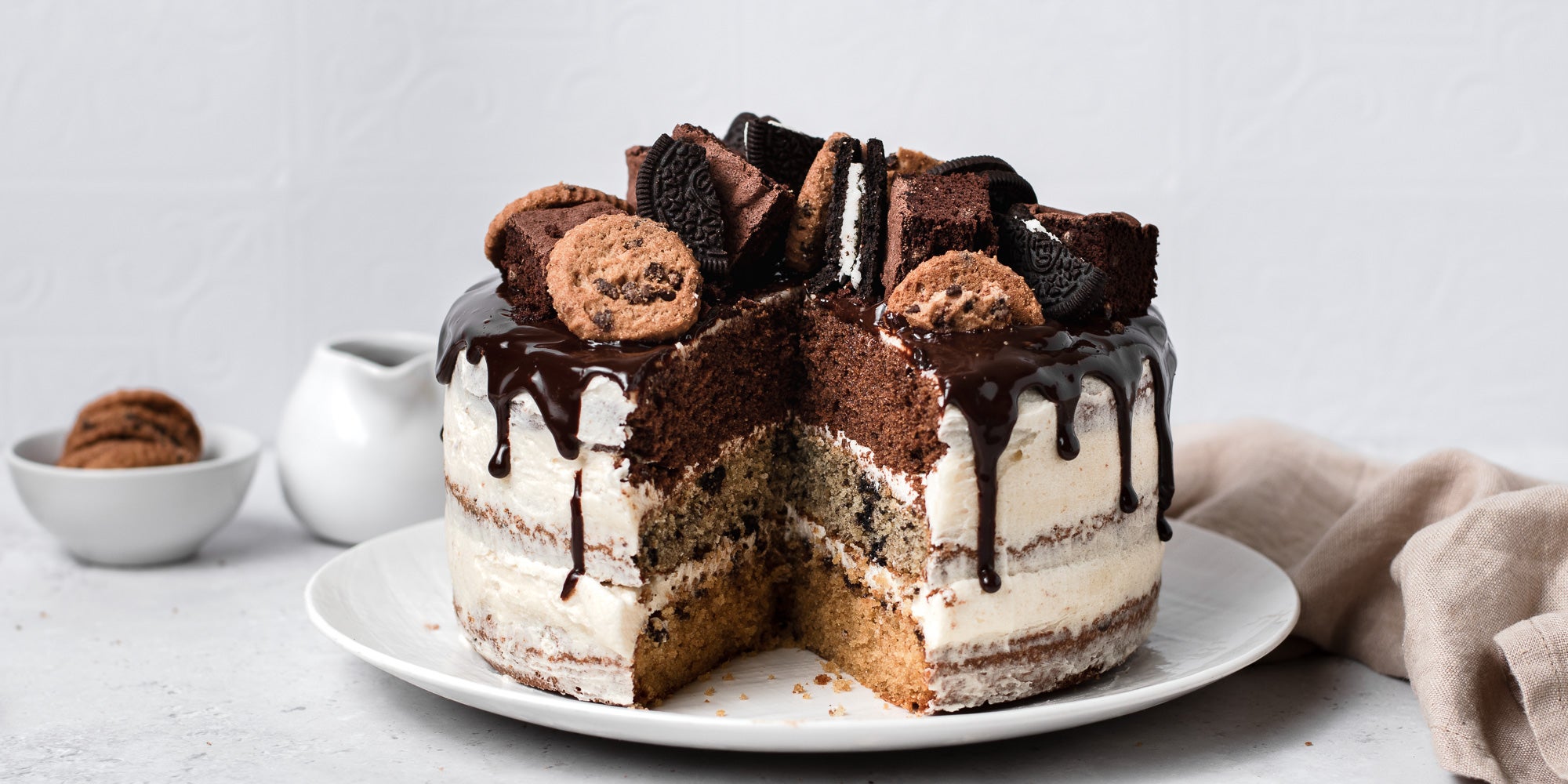 Cookie, Oreo & Brownie Layered Cake with a slice cut out of it.