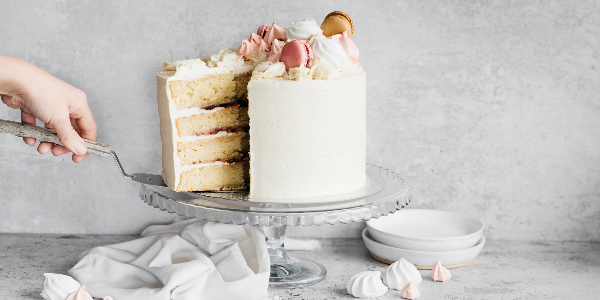 A hand taking a slice out of a vanilla celebration cake