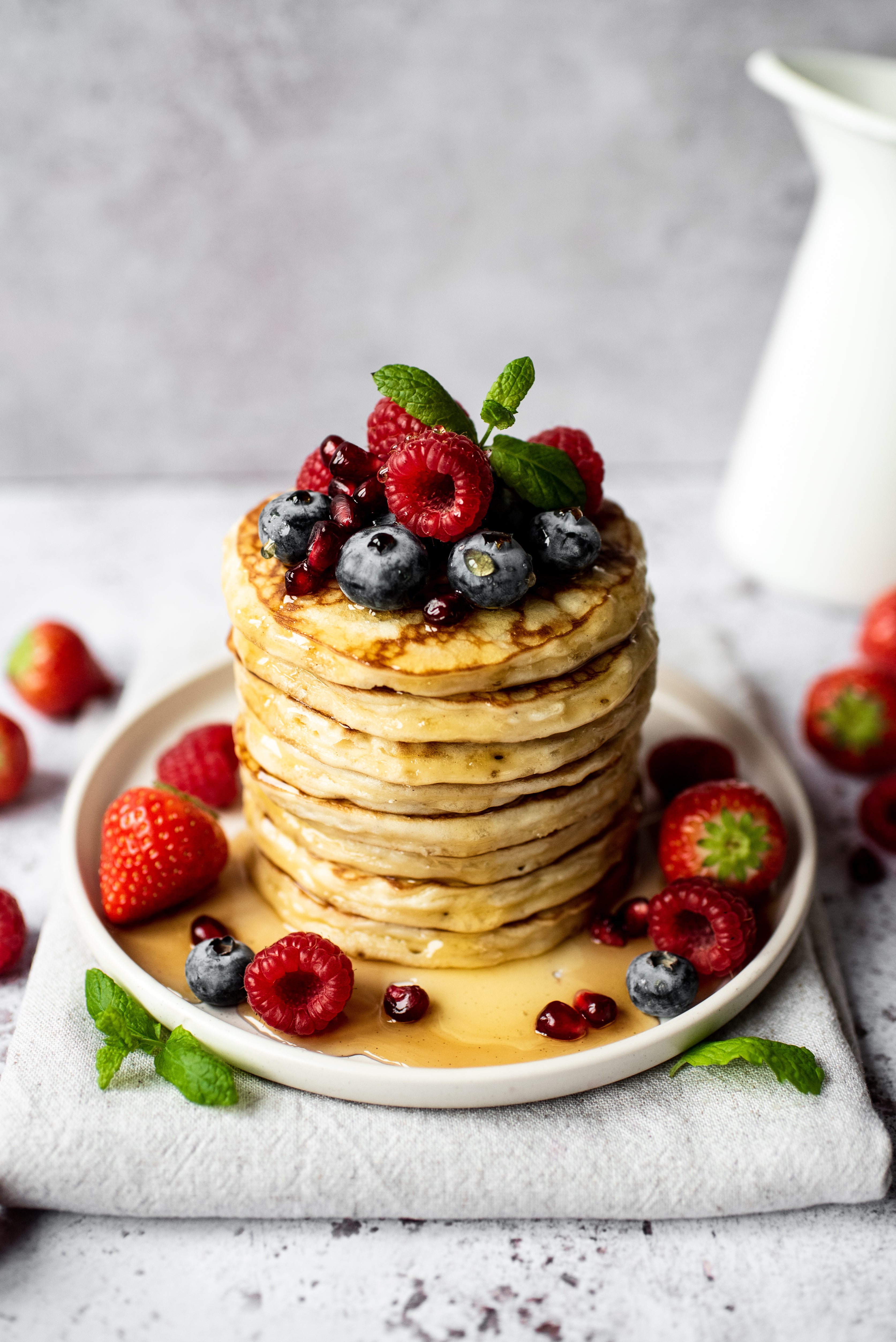 Stack of American pancakes drizzled with maple syrup and topped with fresh berries