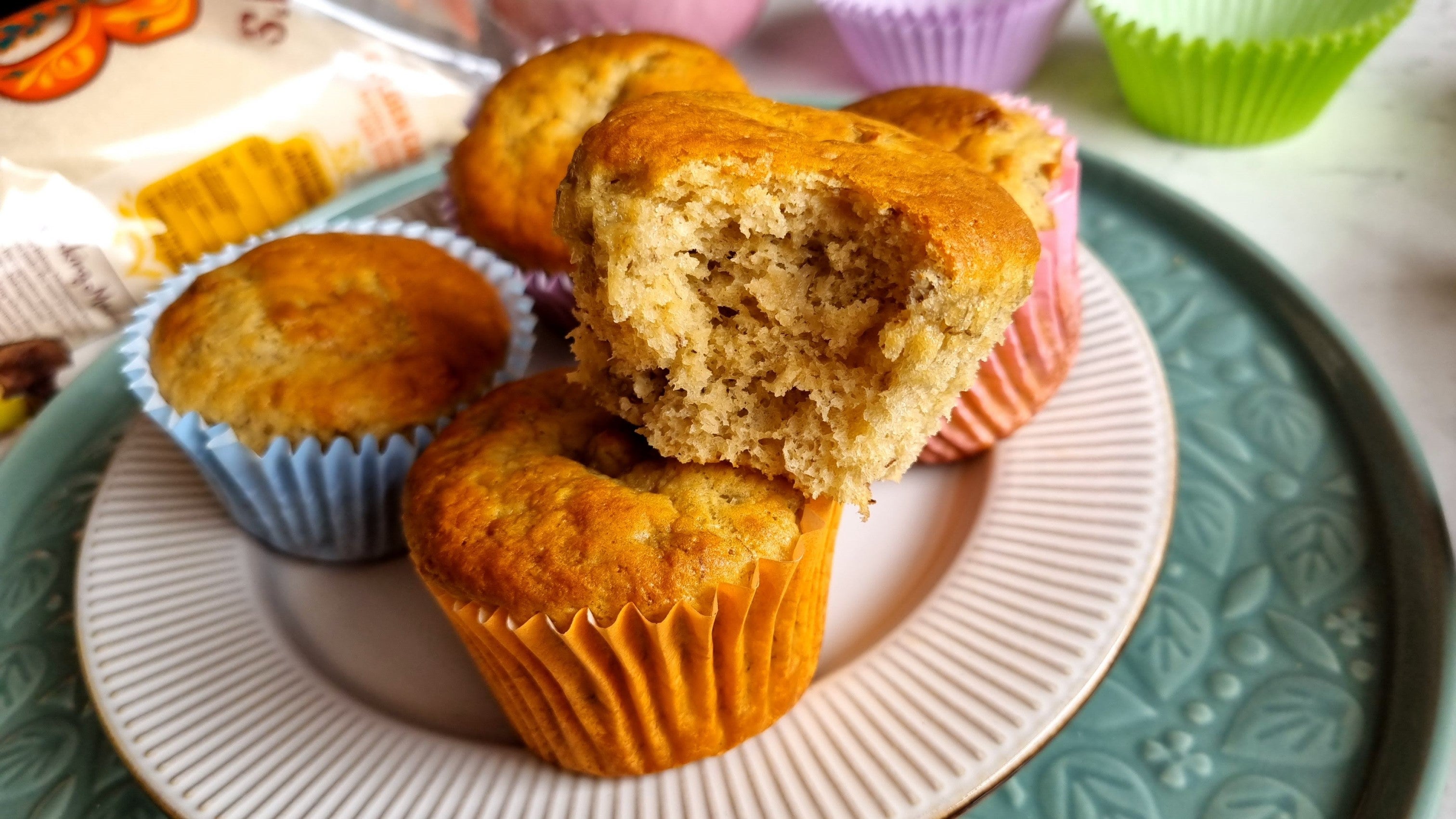 Plate of freshly-baked banana muffins with a bite taken out of one muffin