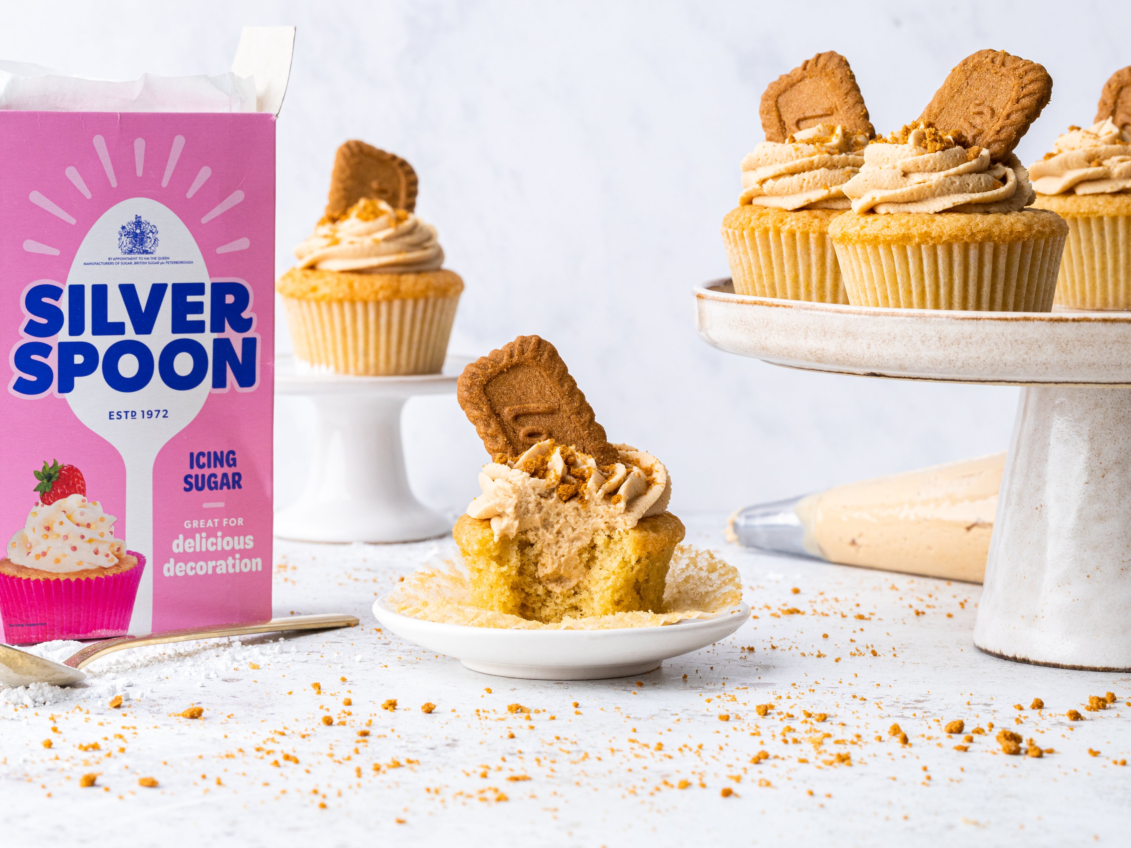 Biscoff cupcake with a bite taken out of it, beside a Silver Spoon sugar pack