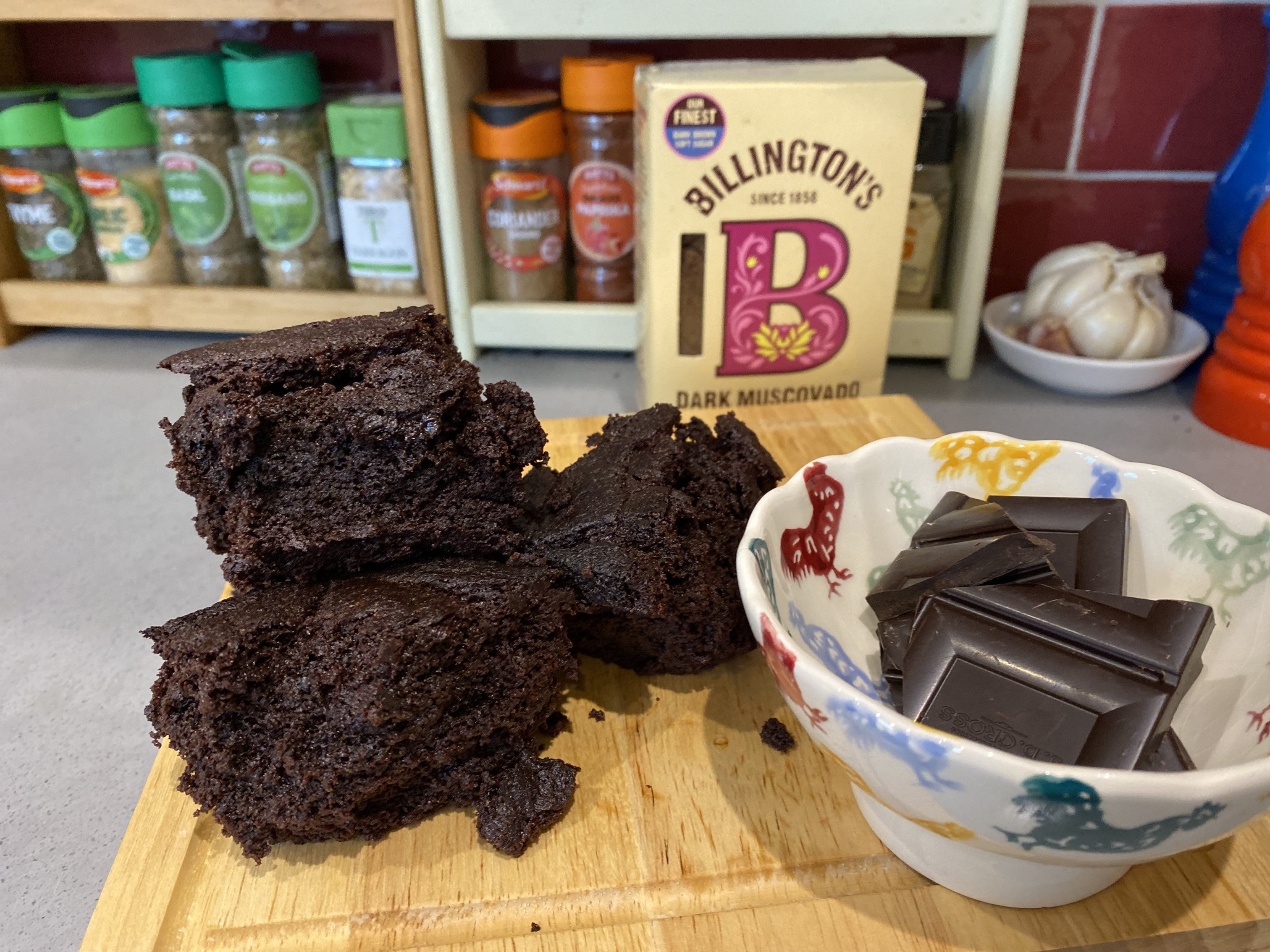 Jamie Oliver brownies on a wooden serving platter next to a bowl of dark chocolate