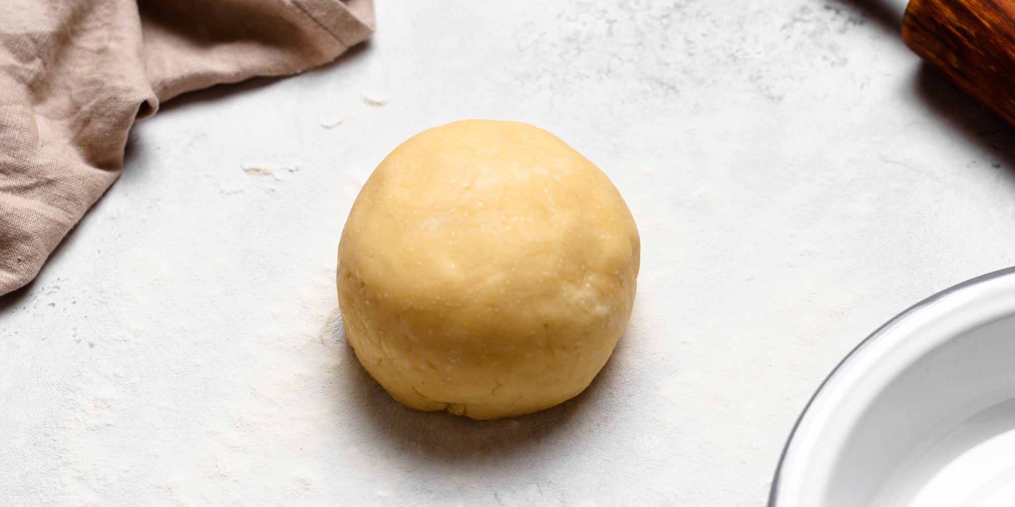 Ball of shortcrust pastry dough on a floured work surface