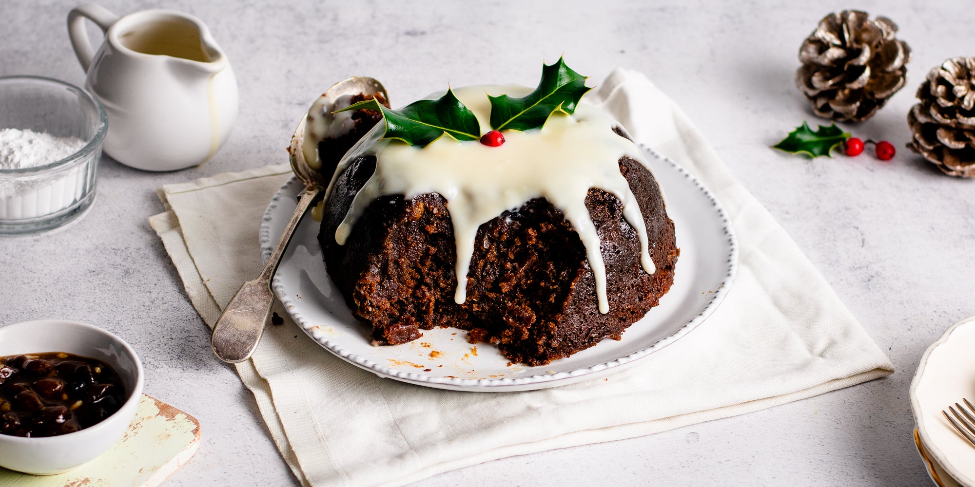 Last Minute Christmas Pudding with a slice taken out of it, showing the insides, with drizzles of cream or brandy butter