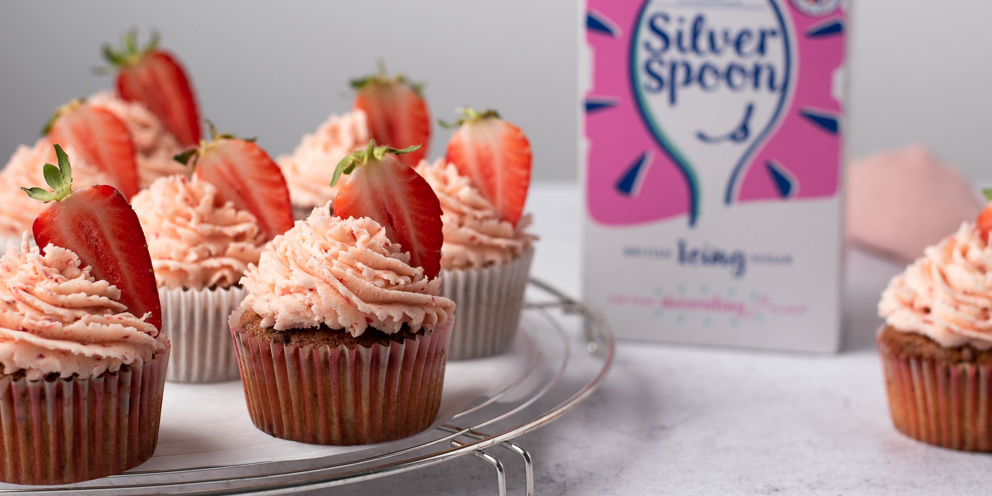 Strawberry cupcakes on a plate topped with strawberry buttercream 