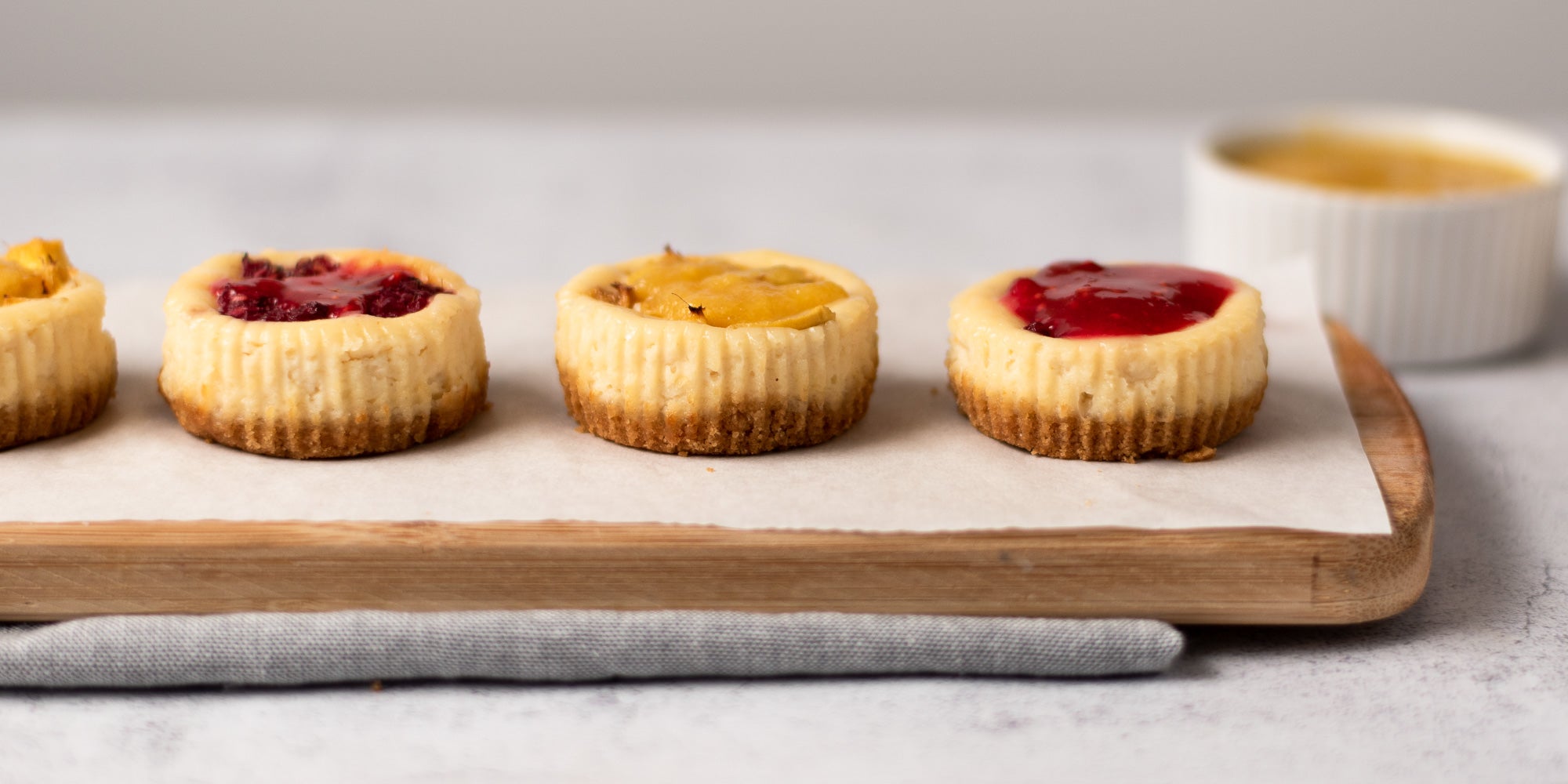 Mini cheesecakes topped with fruit on a wooden board
