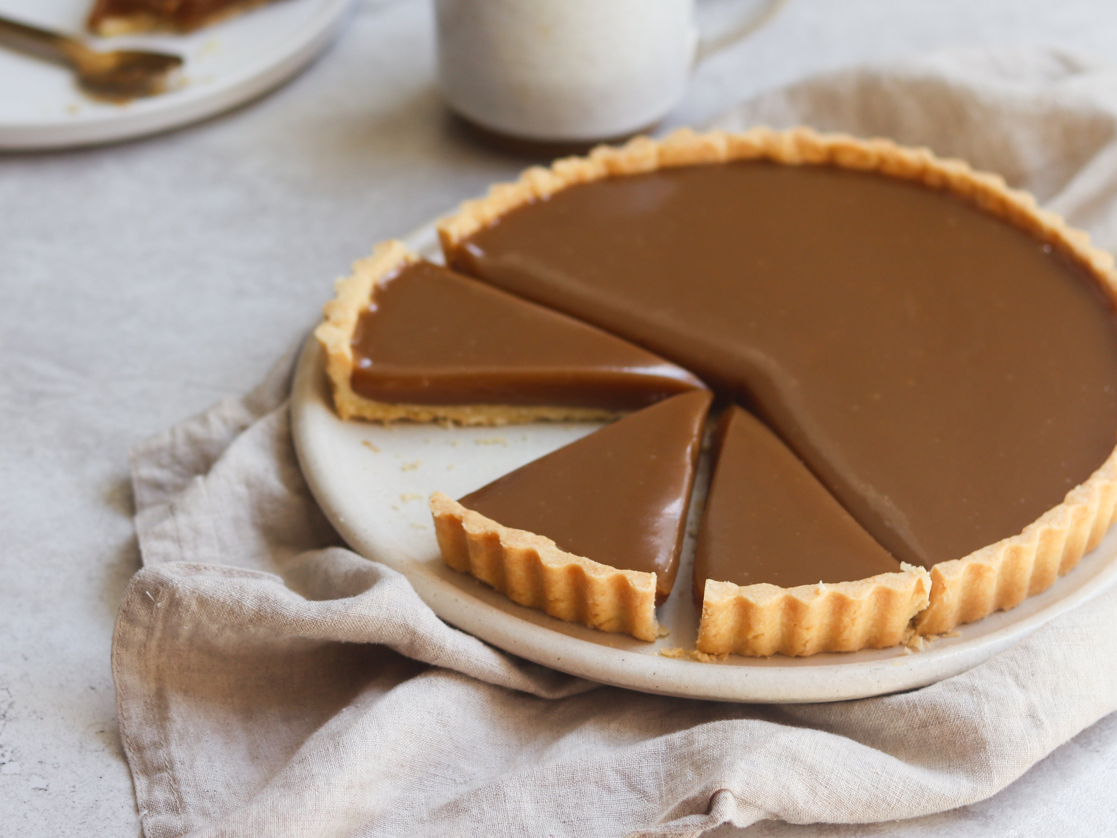 Close up of Butterscotch Tart with slices cut out of it, on linen