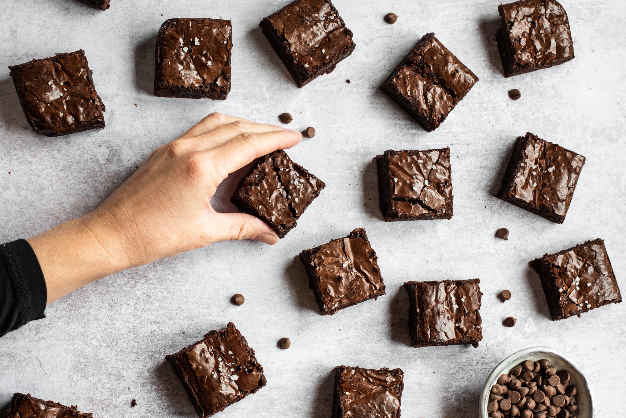 A top down view of chocolate brownies with a hand coming into frame picking up a brownie