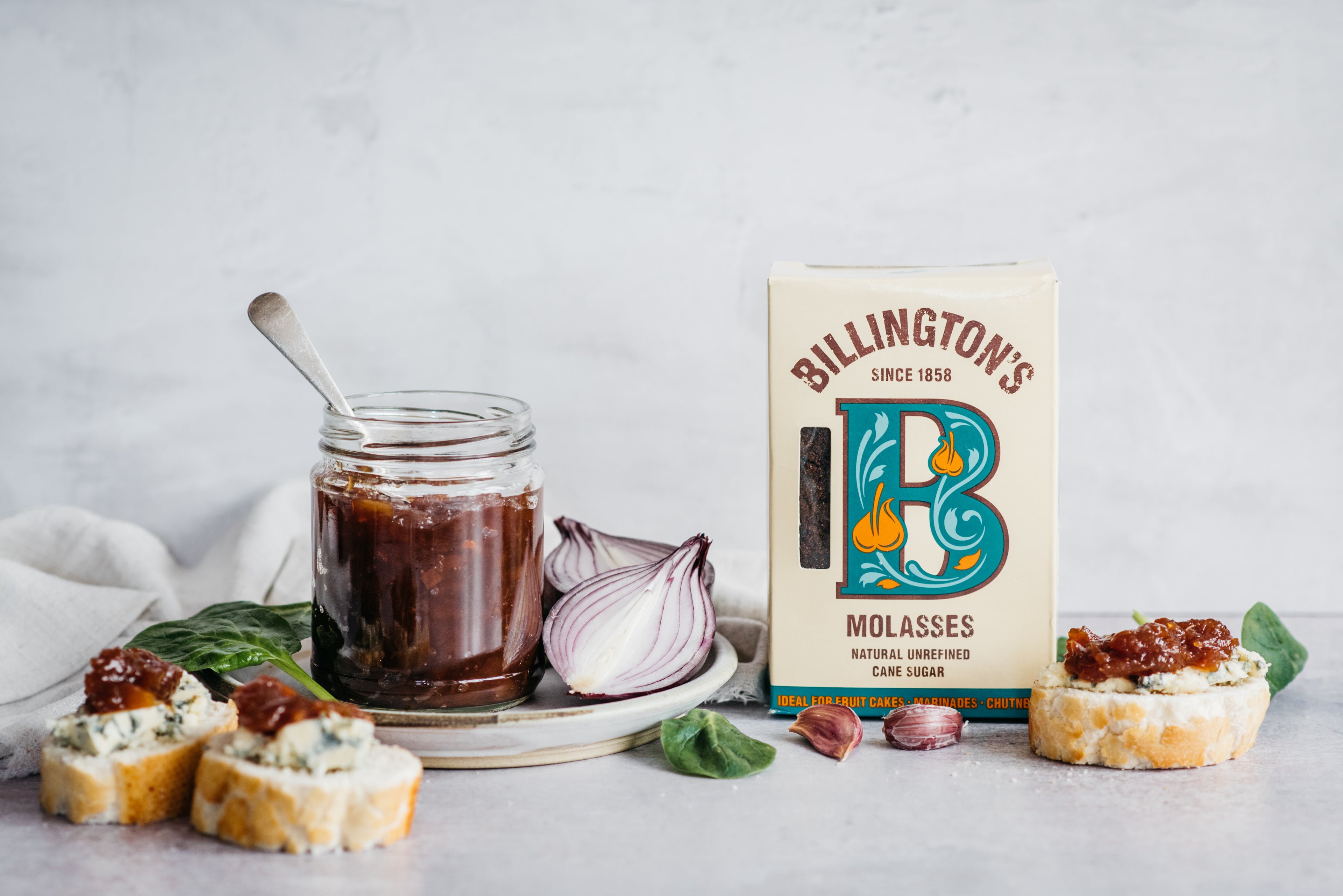 Onion chutney jar on plate with half an onion, bread slices with cheese and onion and sugar pack