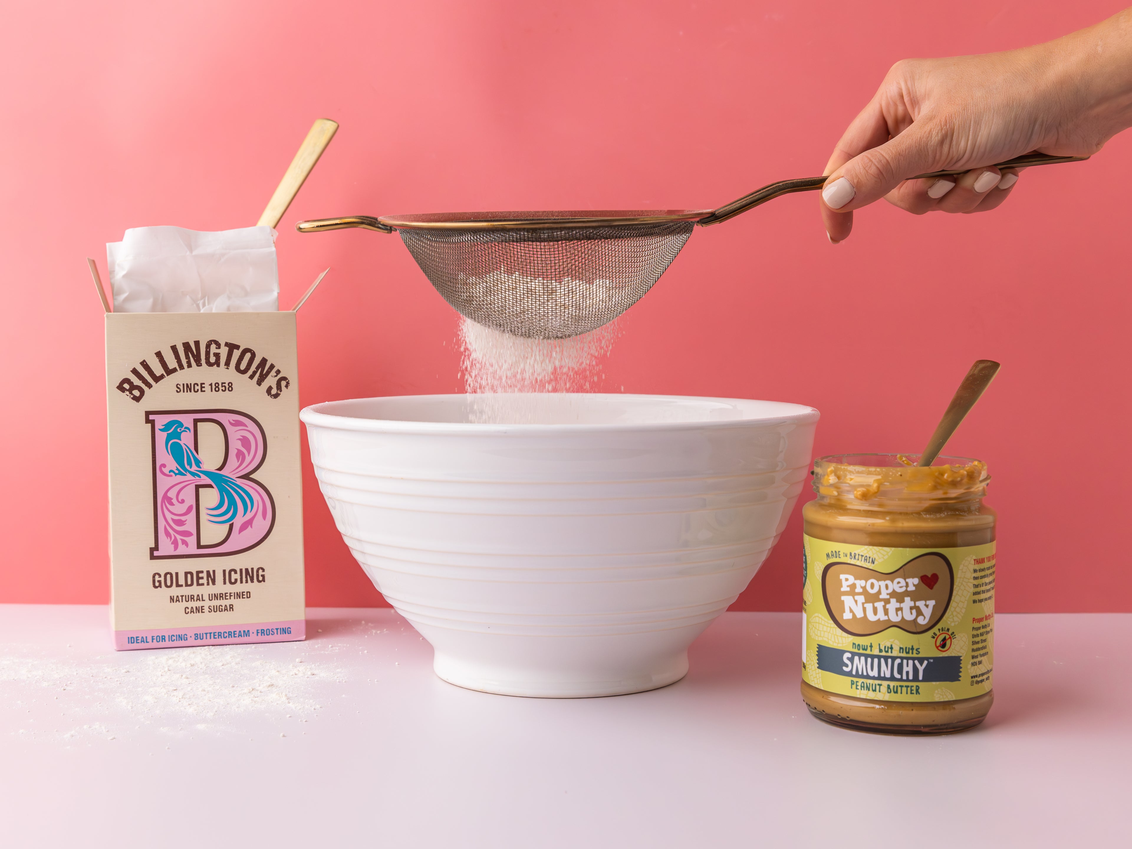 Hand sifting flour into a white bowl