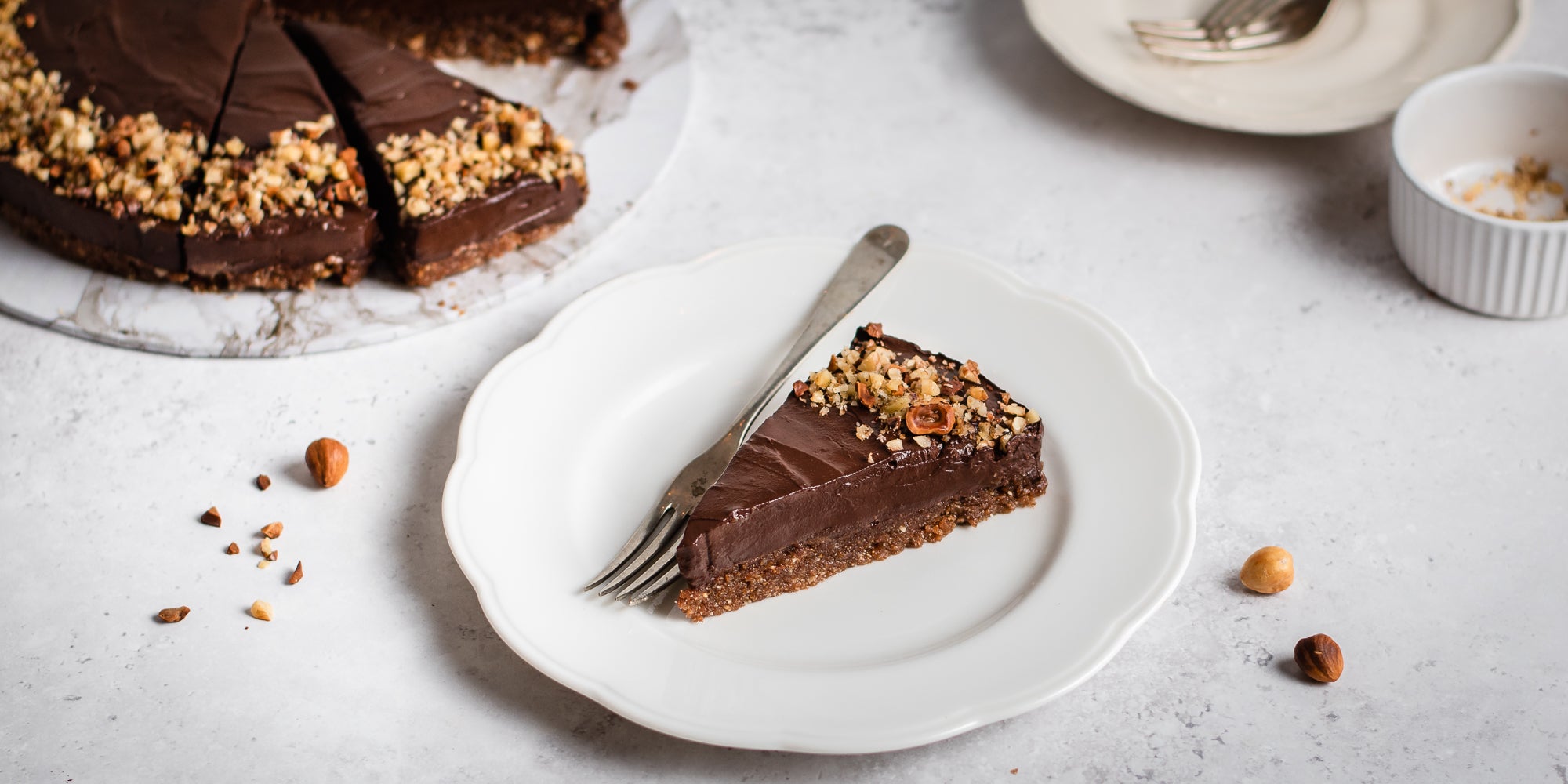 Slice of Raw Chocolate Avocado Cheesecake slice on a plate next to a fork to serve