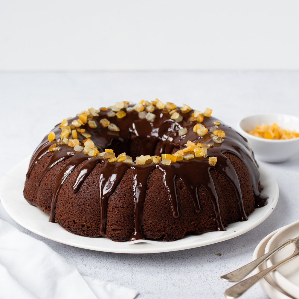 chocolate orange bundt cake on plate with chocolate drizzle on top with candid orange peel