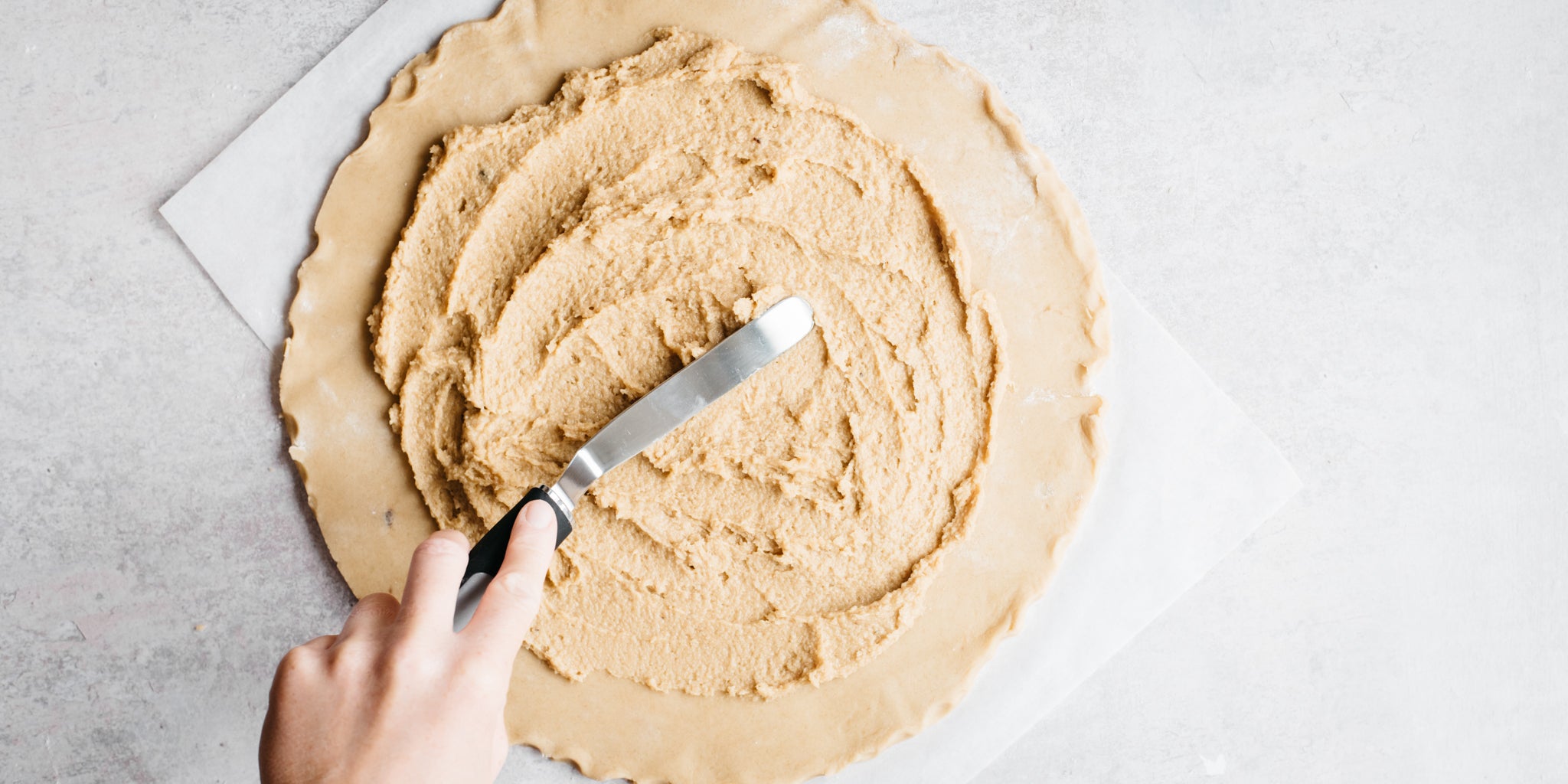 Palette knife spreading mixture on to a circle of pastry