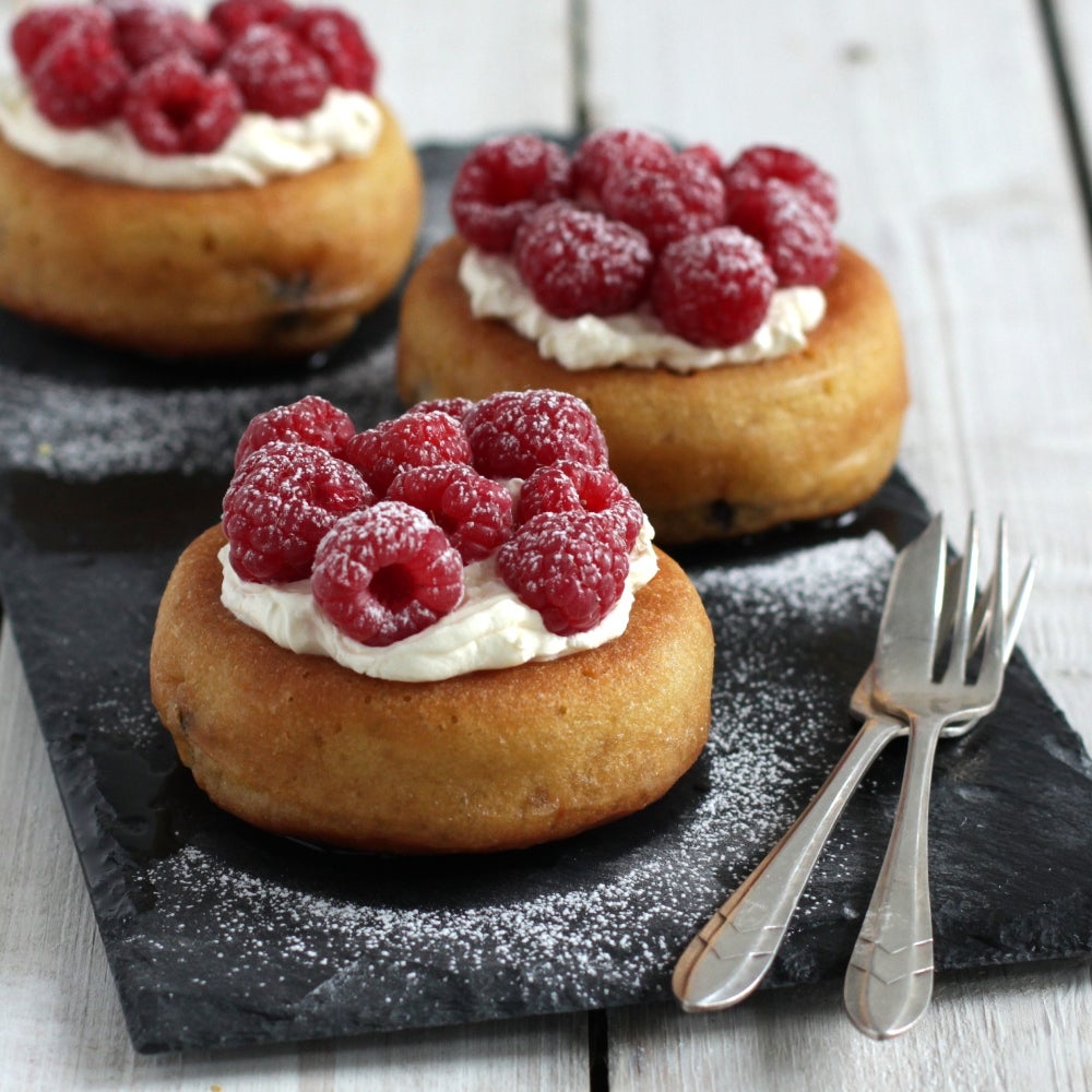 Rum babas served with raspberries and fresh cream