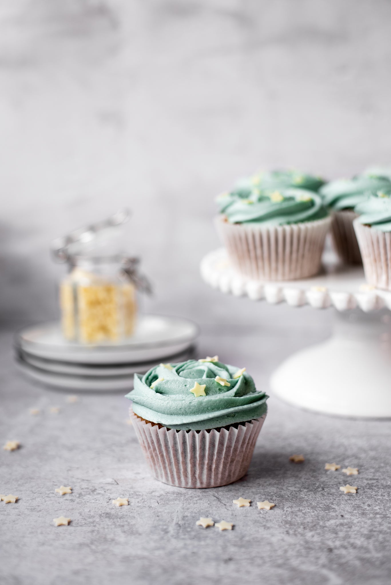 Single Earl Grey cupcake decorated with buttercream icing and white chocolate stars on a grey work surface