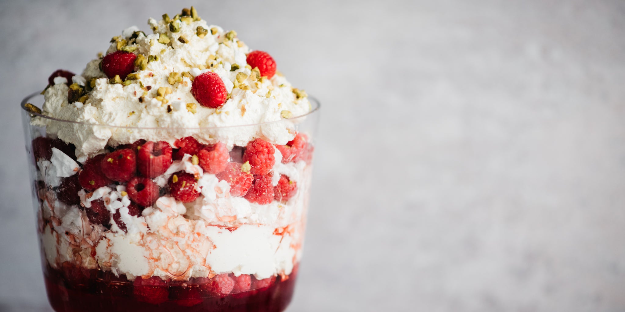 Close up of a fully layered Eton Mess Trifle sprinkled with a chopped nuts and fresh rasperries