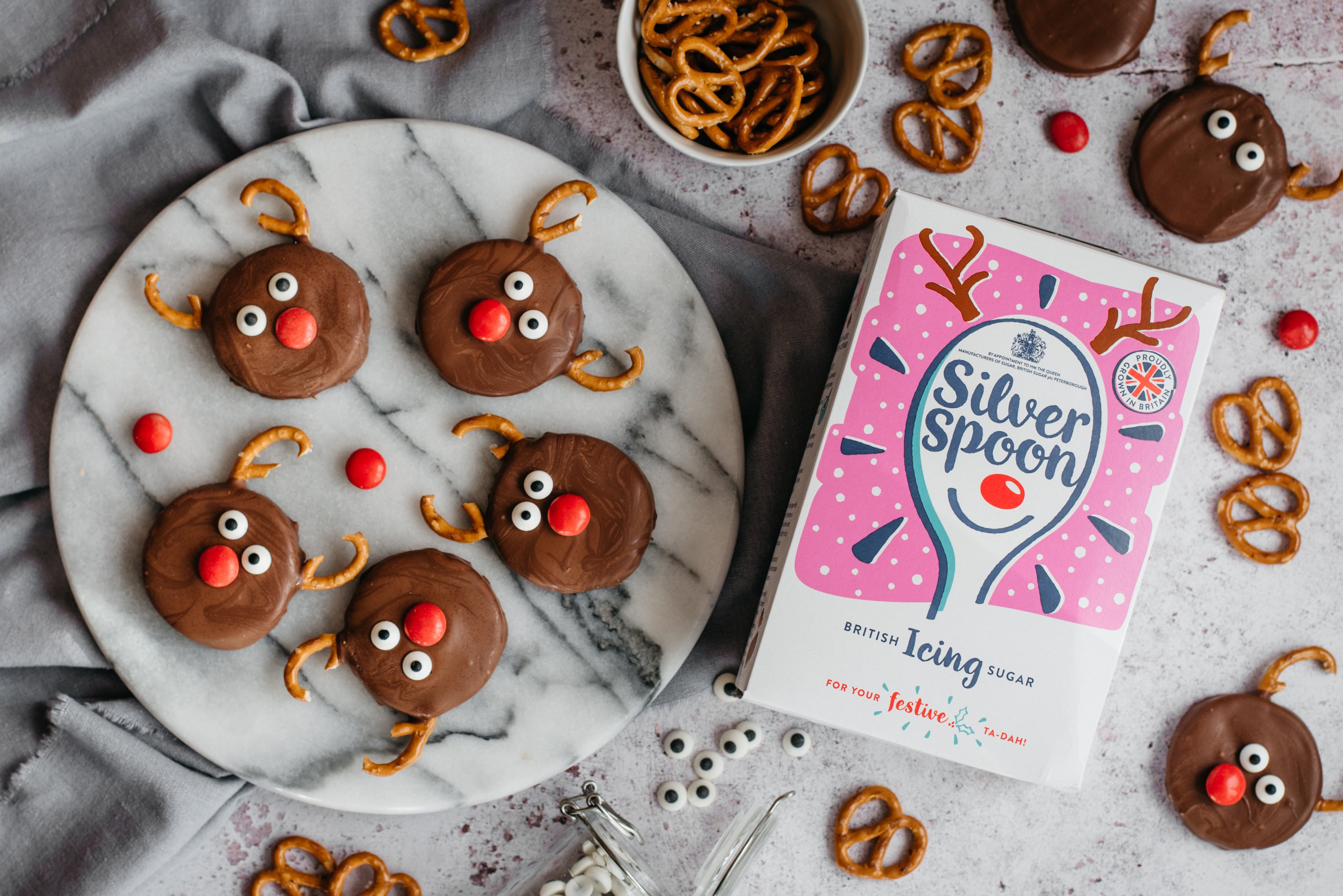 Reindeer Orange Creams decorated with pretzels,  top view next to a box of Silver Spoon icing sugar