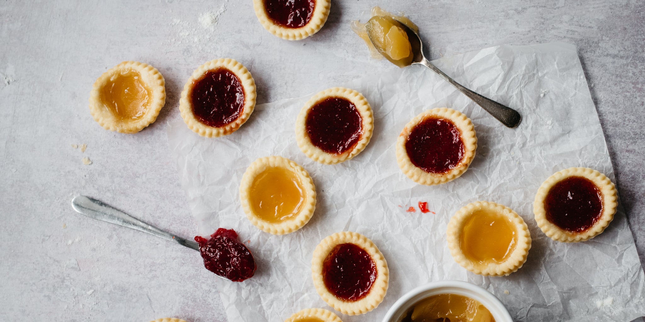 Apricot & Strawberry Jam Tarts served on parchment paper with spoons covered in jam