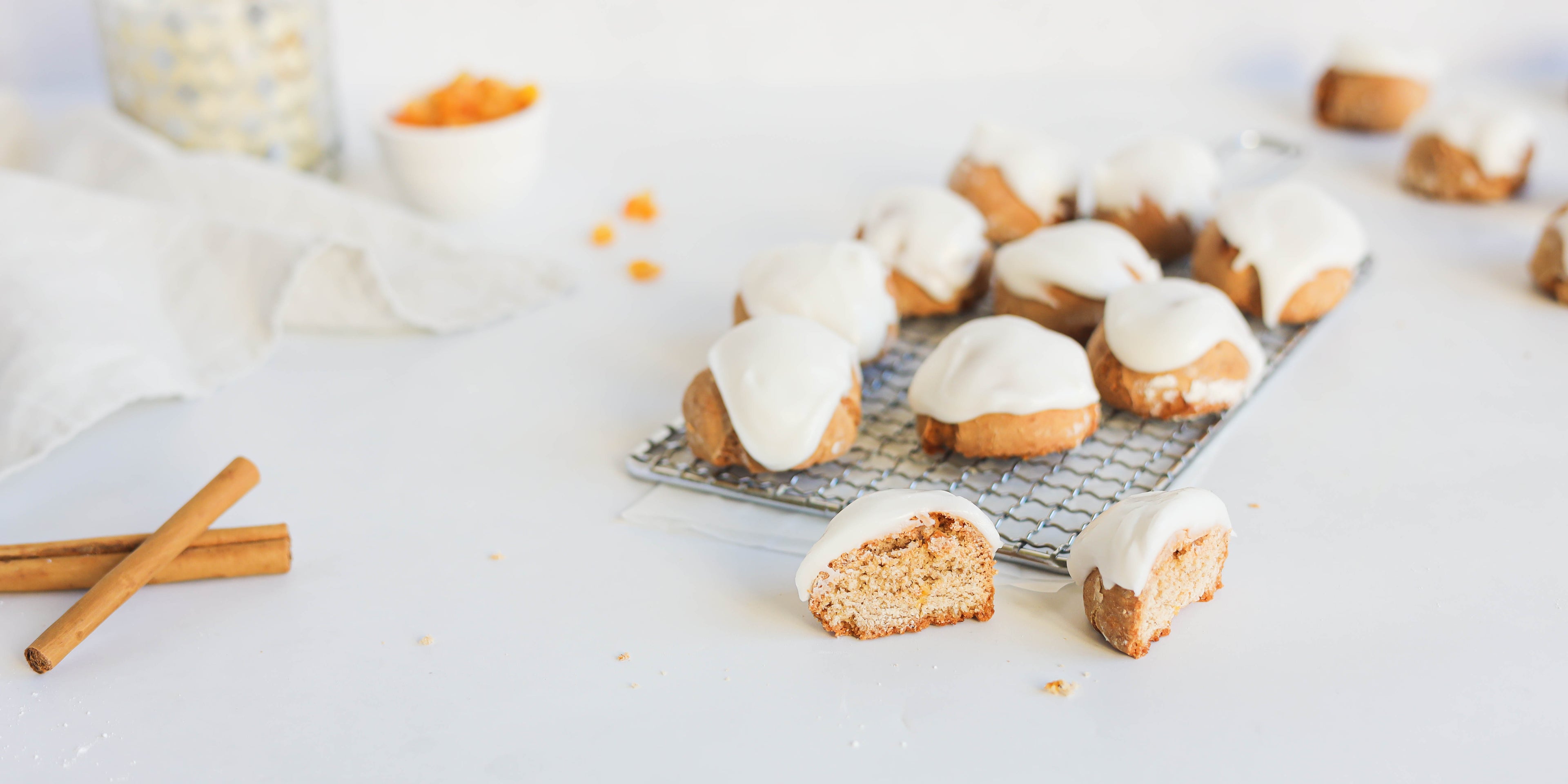 Pfeffernusse on a wire rack, with a Pfeffernusse in the foreground cut in half showing the centre. Topped with Silver Spoon Icing sugar