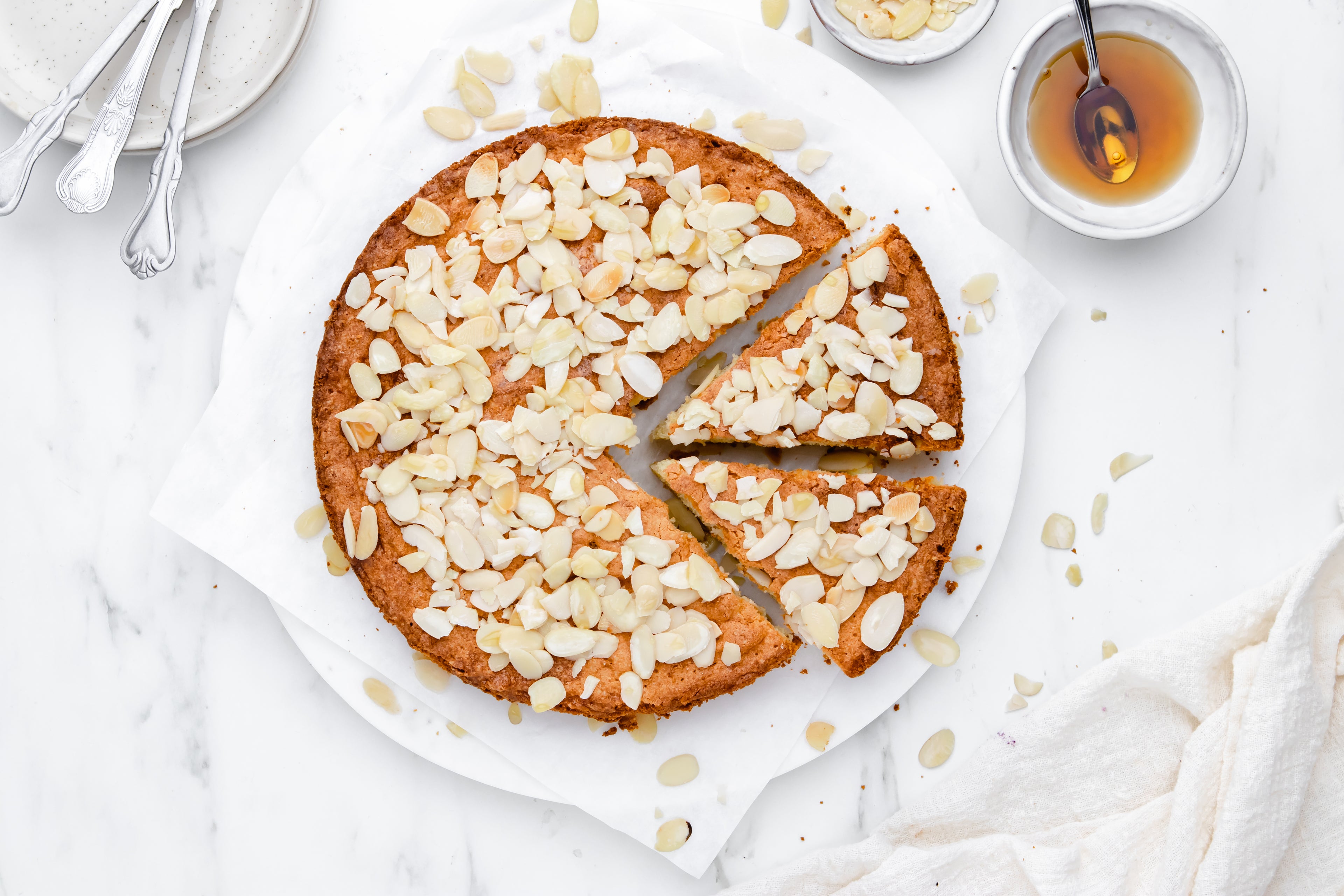 Almond cake with two slices cut out, sprinkled with almonds 