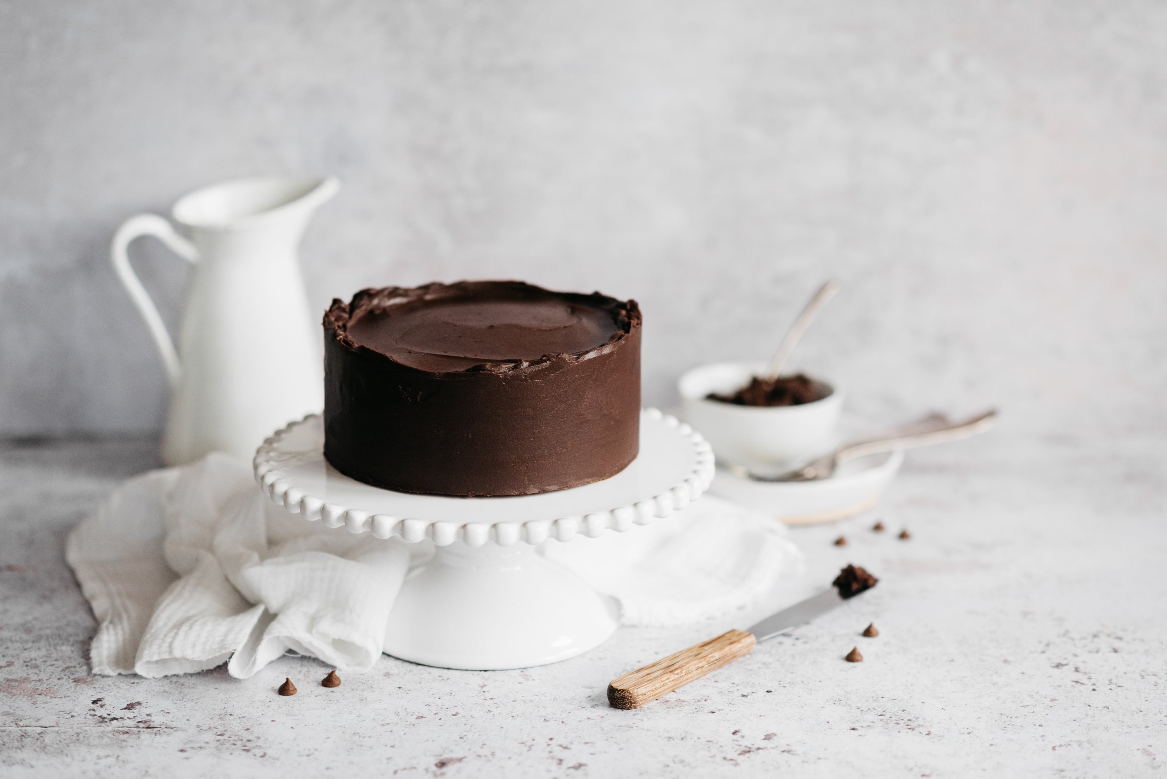 Chocolate Biscuit Cake served on a cake stand, with a palette knife with chocolate ganache