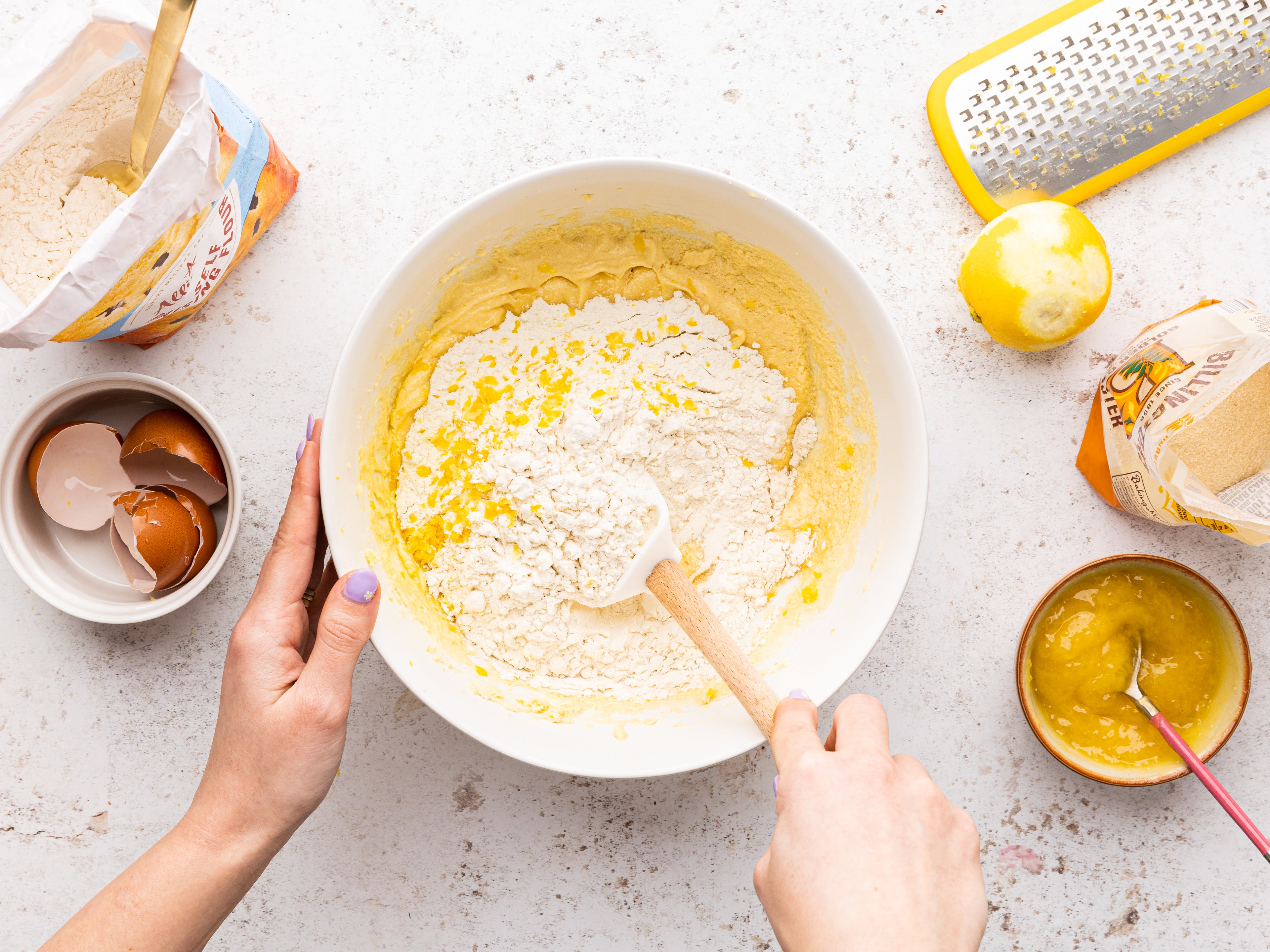 Ingredients being mixed in a bowl with a wooden spoon and a grated lemon beside