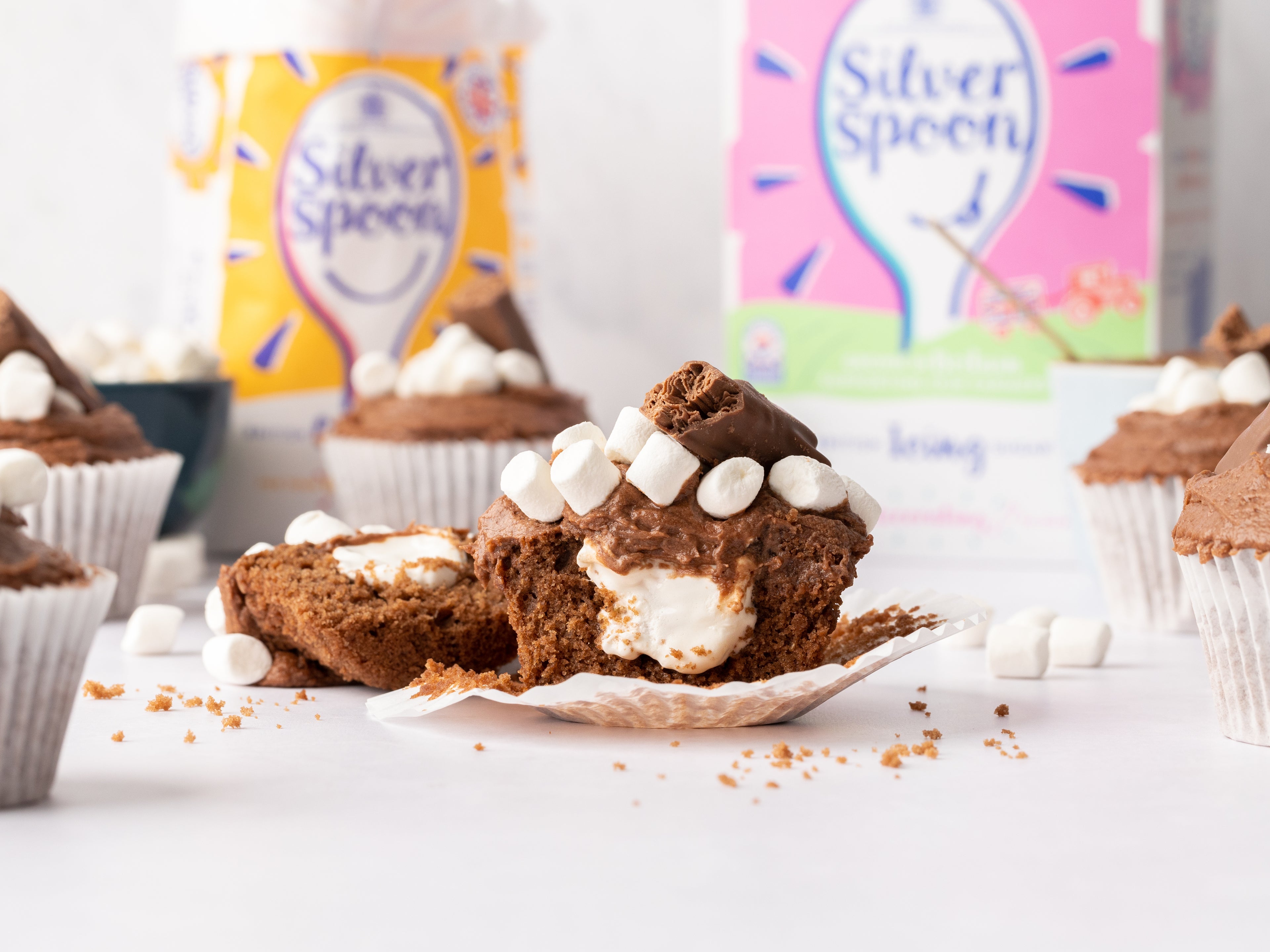 Close up of chocolate cupcake pulled apart with marshmallow centre and sugar packs in background