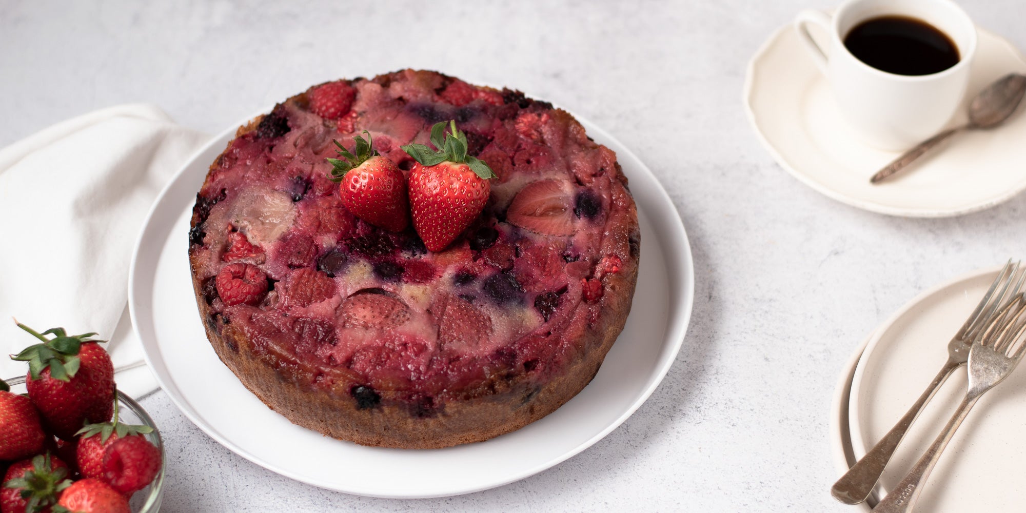 upside down berry pudding on a plate topped with two strawberries