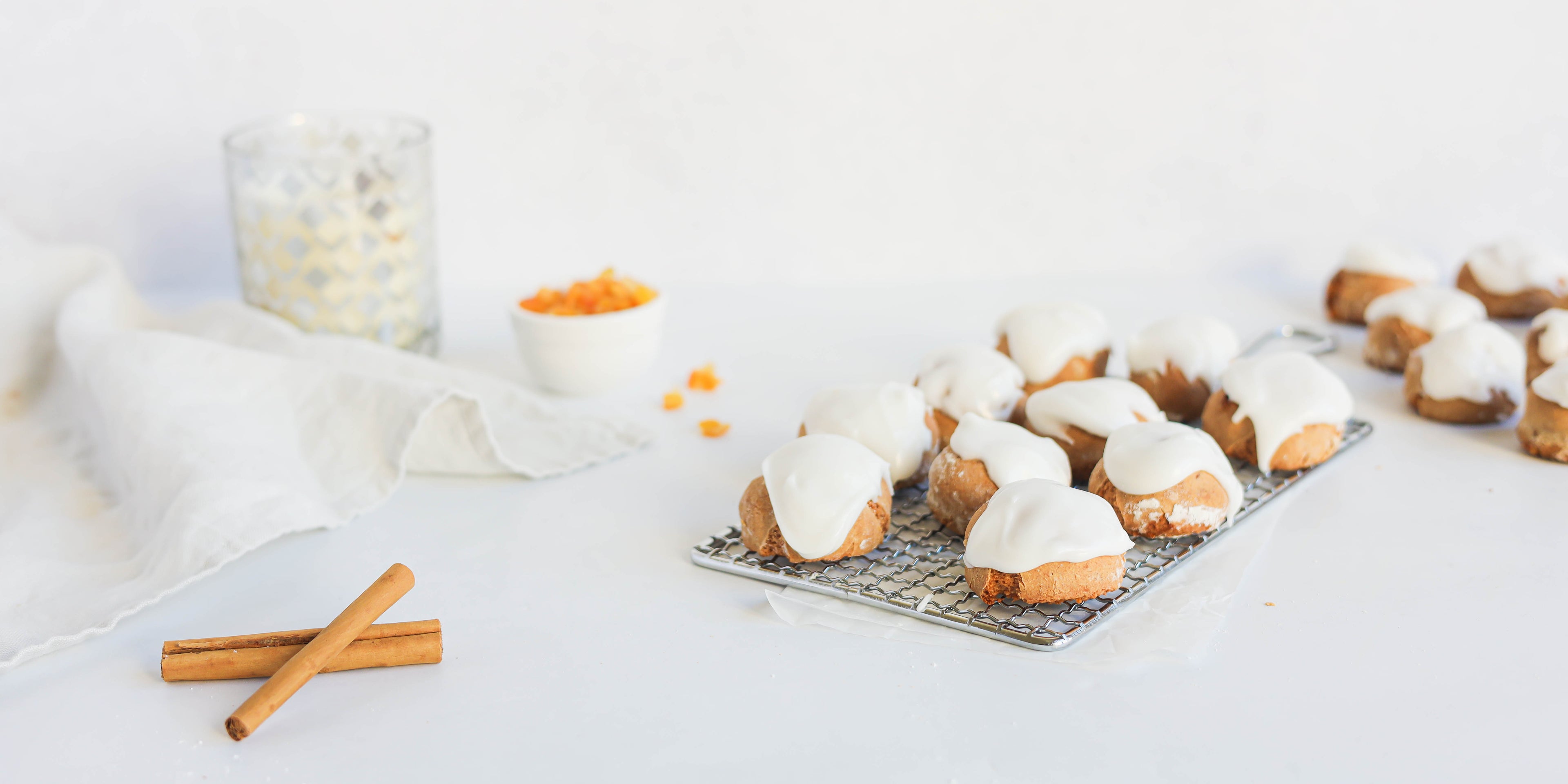 Pfeffernusse on a wire rack, next to cinnamon sticks. Iced with Silver Spoon icing sugar