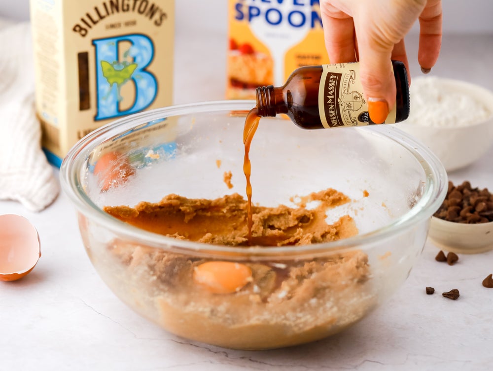 Vanilla extract being poured into a bowl of cookie mix