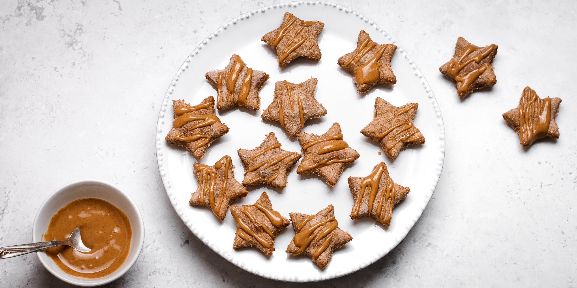 Star shaped festive Dog Biscuits drizzled with Proper Nutty peanut butter on a plate