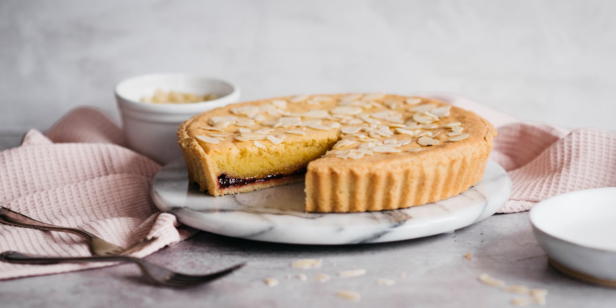 Close up of a slice cut out of a Simple Bakewell Tart, showing the delicious jammy insides