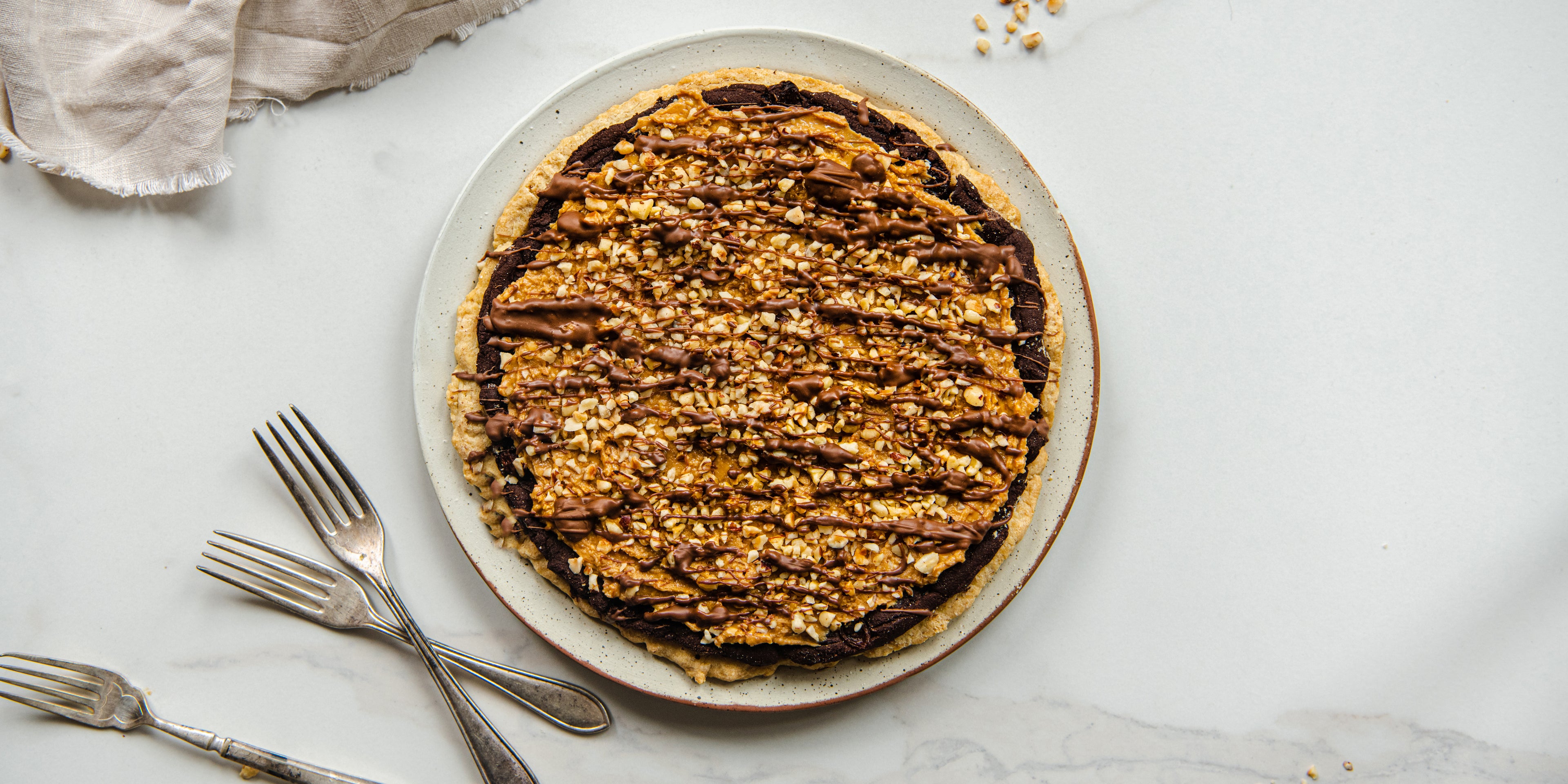 Top view of Easter Mazurek scattered with peanuts, next to some forks to serve