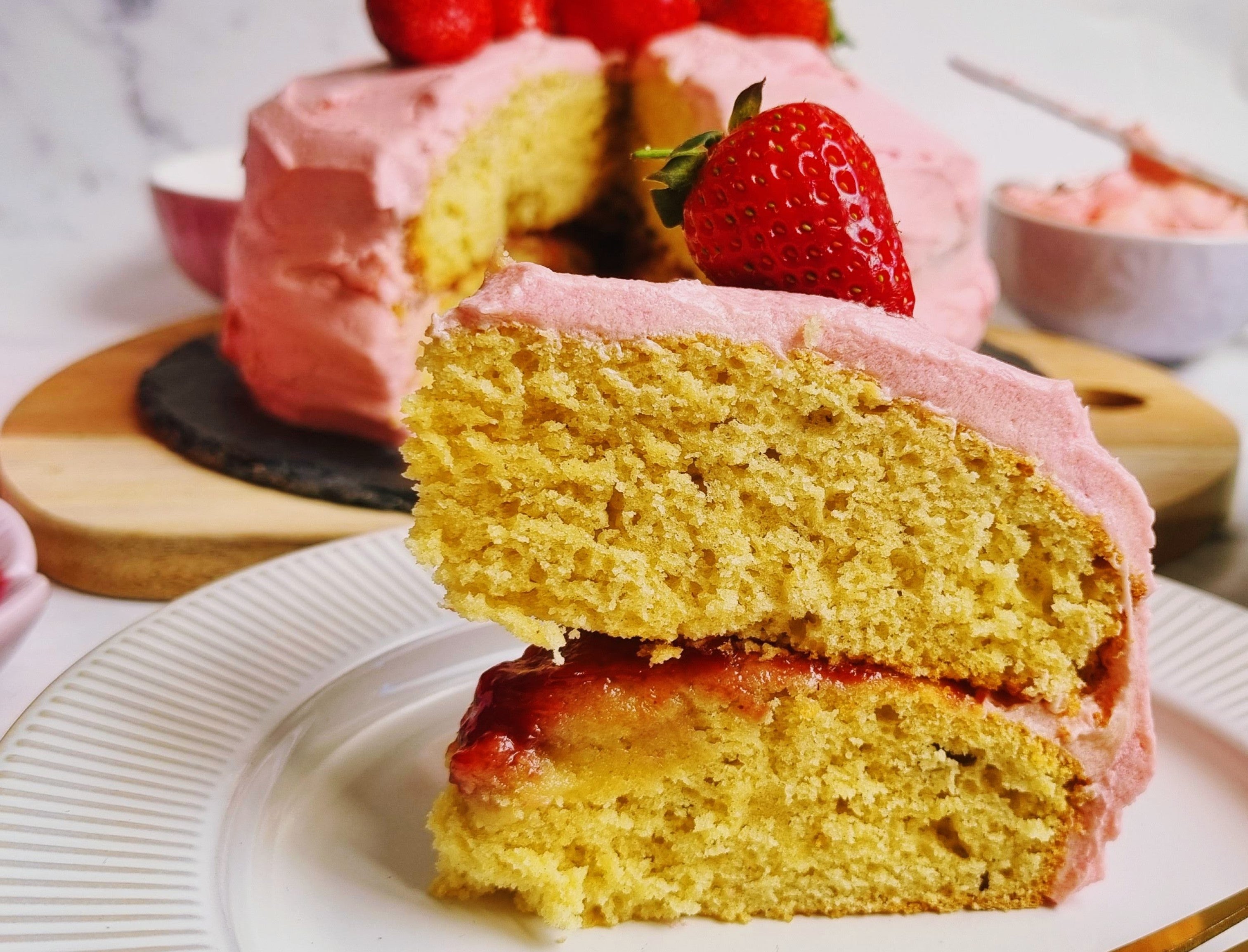 Slice of homemade strawberry cake with a jam filling and strawberry buttercream icing 
