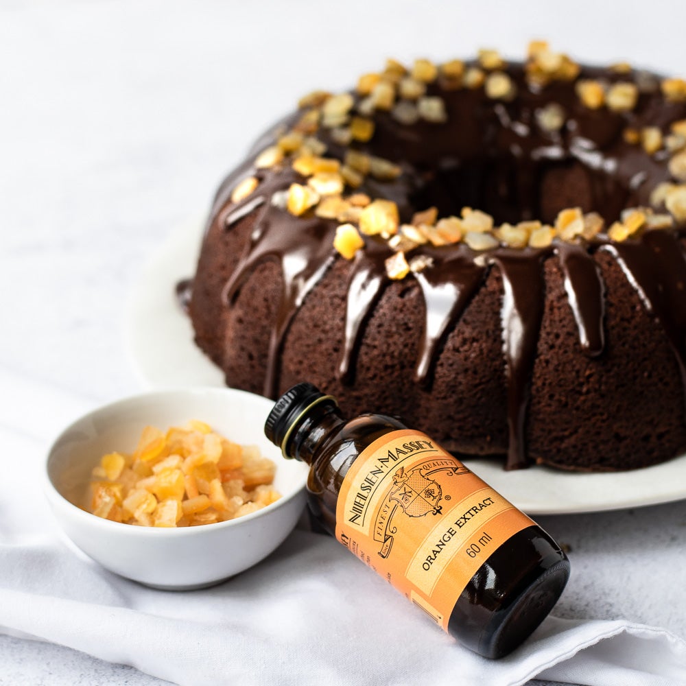 chocolate orange bundt cake on plate with chocolate drizzle on top with candid orange peel