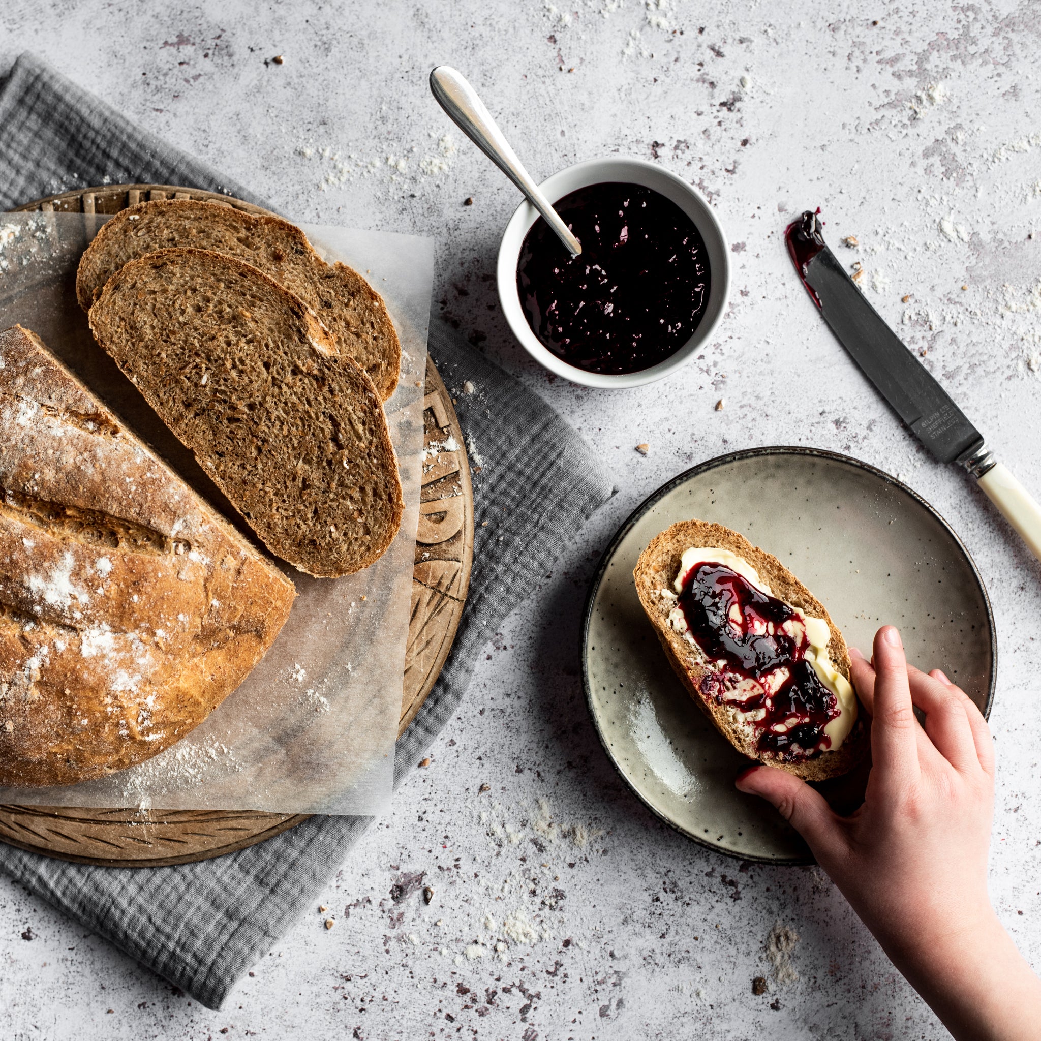 loaf of bread with slice removed topped with butter and jam