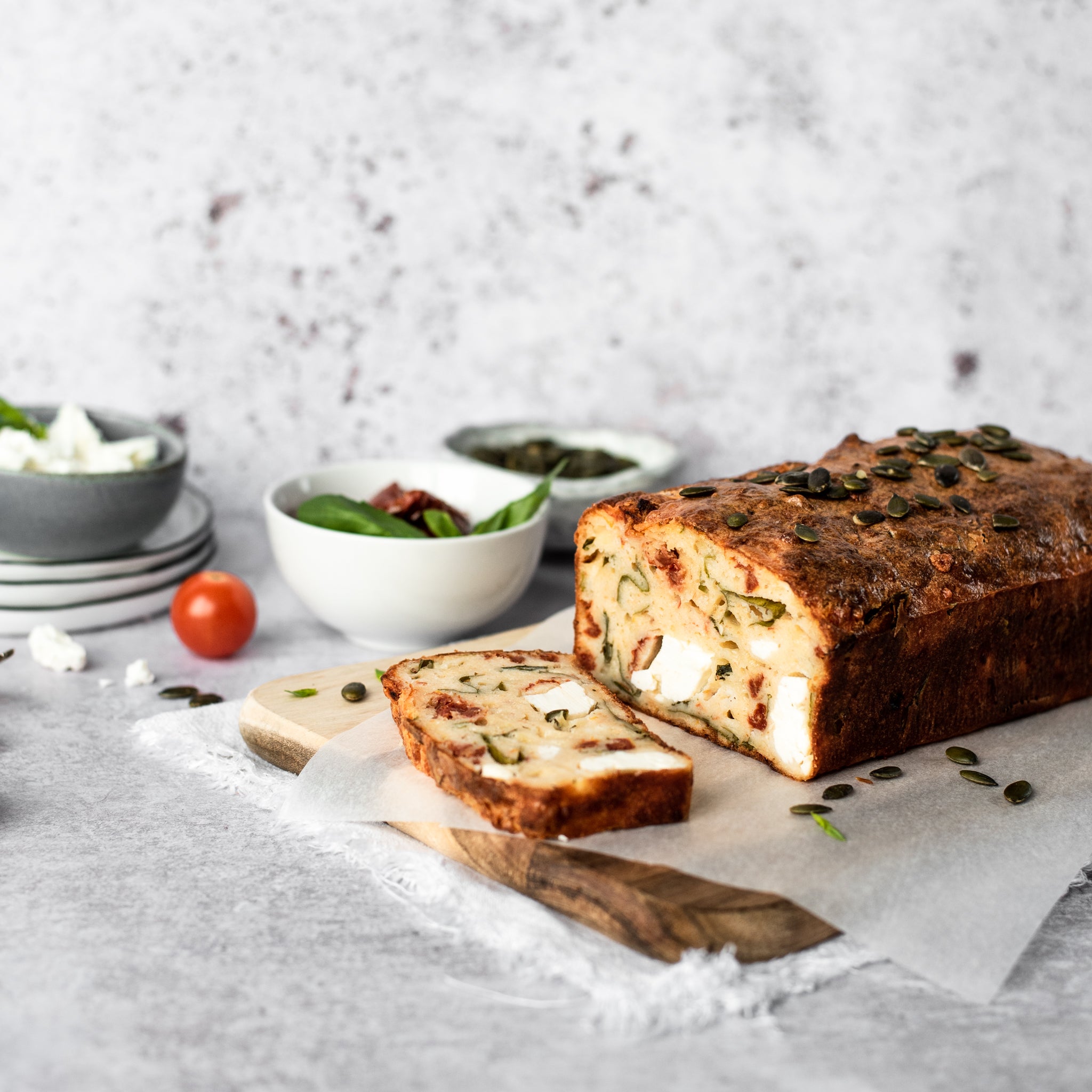 Feta and tomato loaf with slice removed on a chopping board