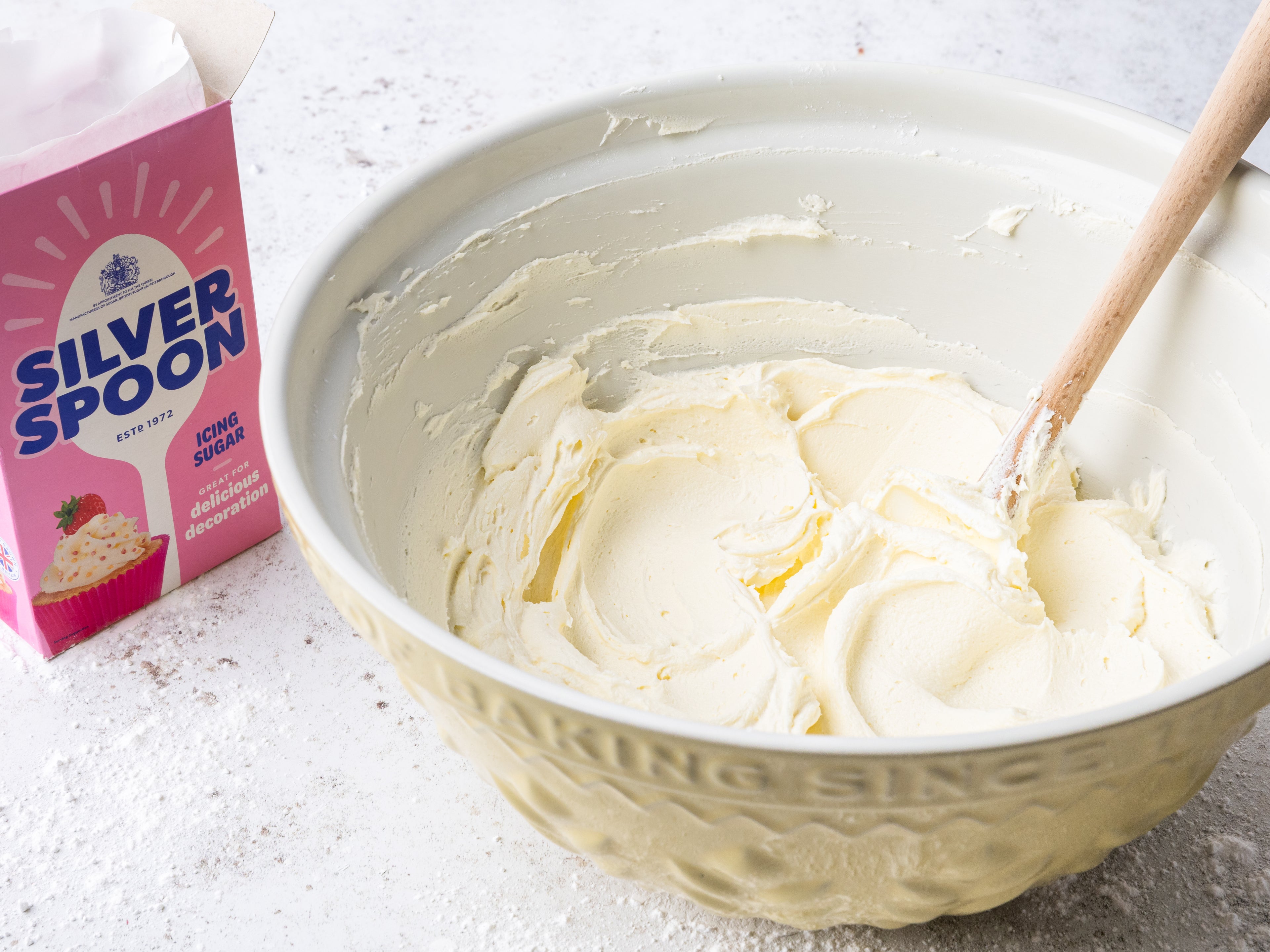 Buttercream in a bowl beside a pack of icing sugar