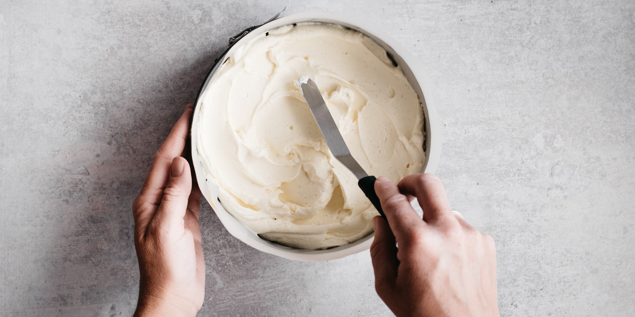 Hand smoothing down cheesecake mixture with a spatula
