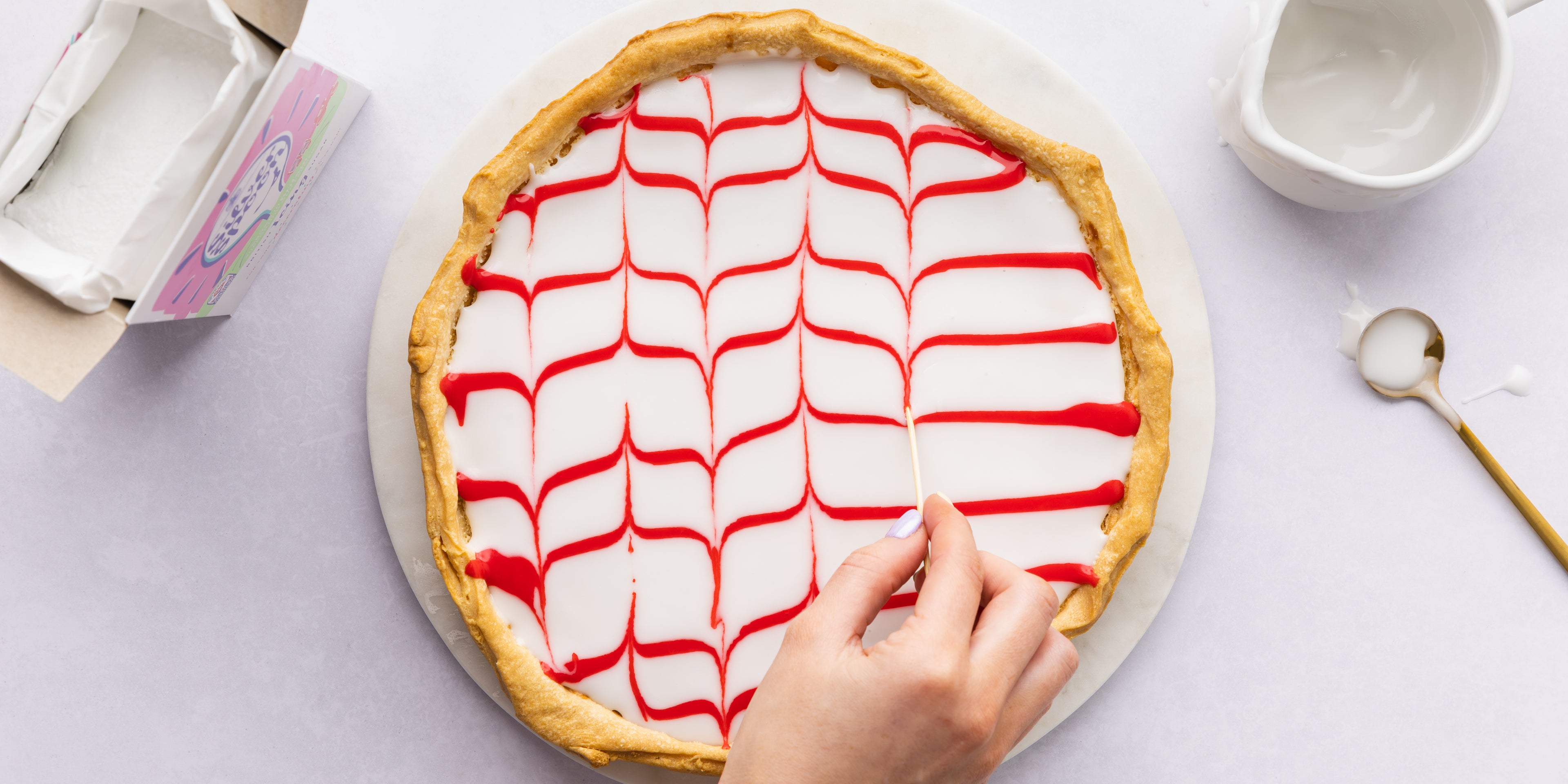 Hand using a skewer to make a ribbon effect pattern